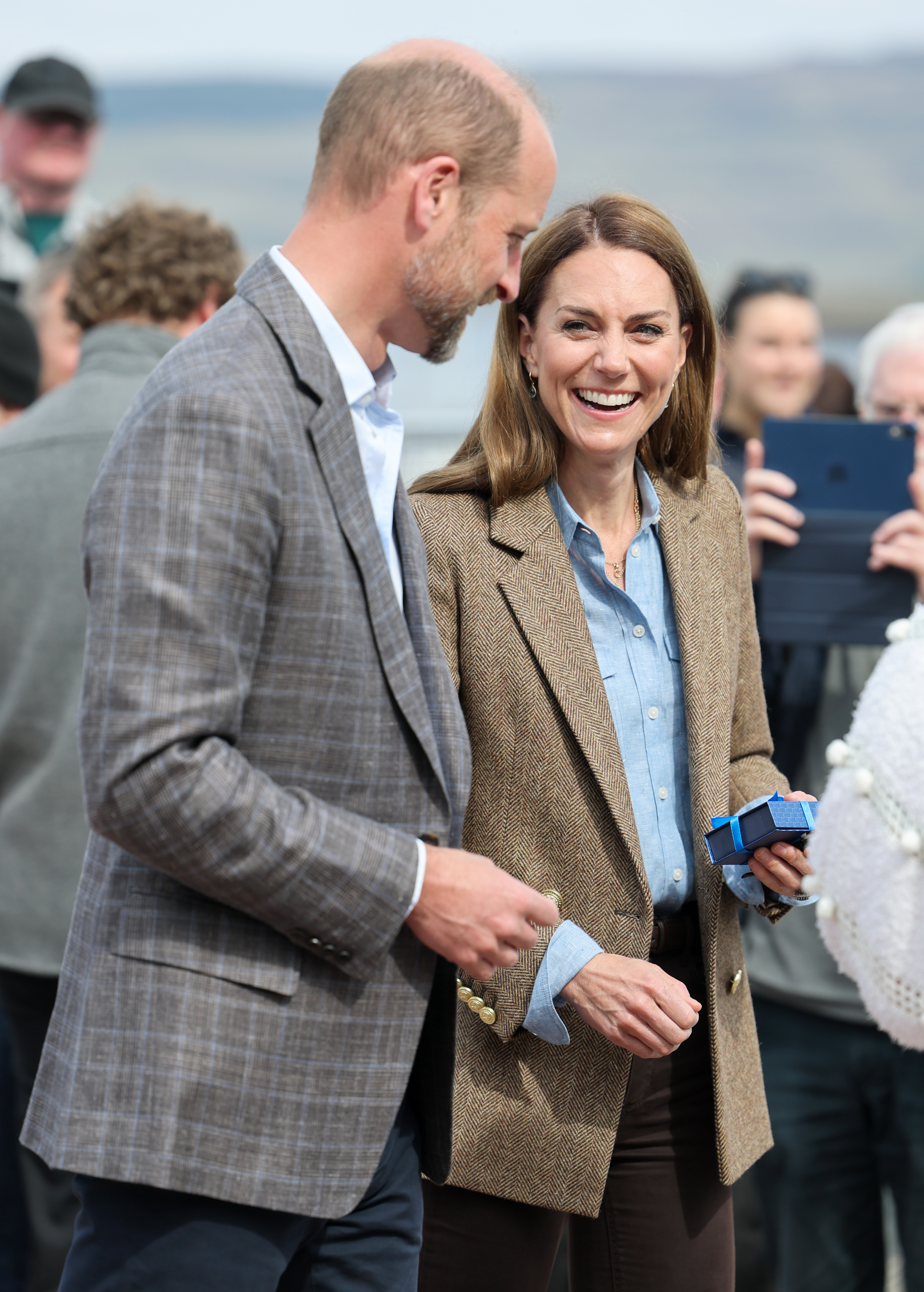 Catherine beams as she holds a small gift while standing beside William at a community engagement in Tobermory. The couple's approachable demeanor was on full display as they mingled with residents during their visit to Aros Hall.