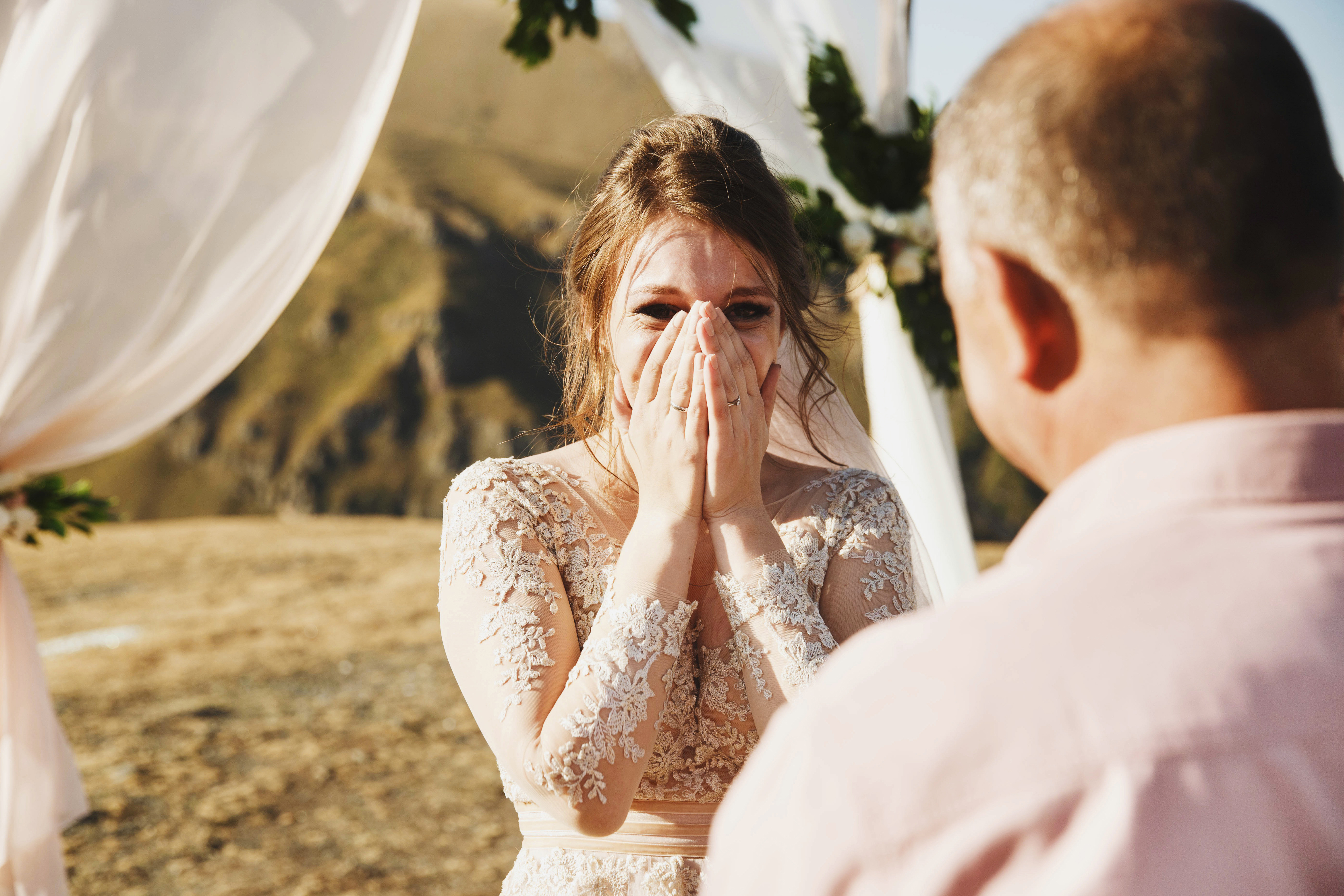 A bride looks at her father with her hands covering her mouth. | Source: Shutterstock