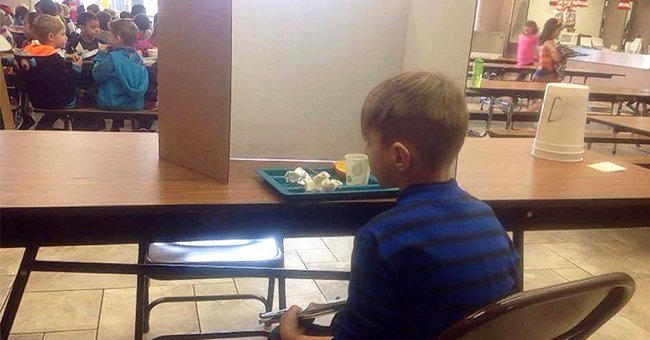 Hunter pictured sitting alone at the table, with a large cardboard divider separating him from his classmates. | Source: facebook.com/NYDailyNews