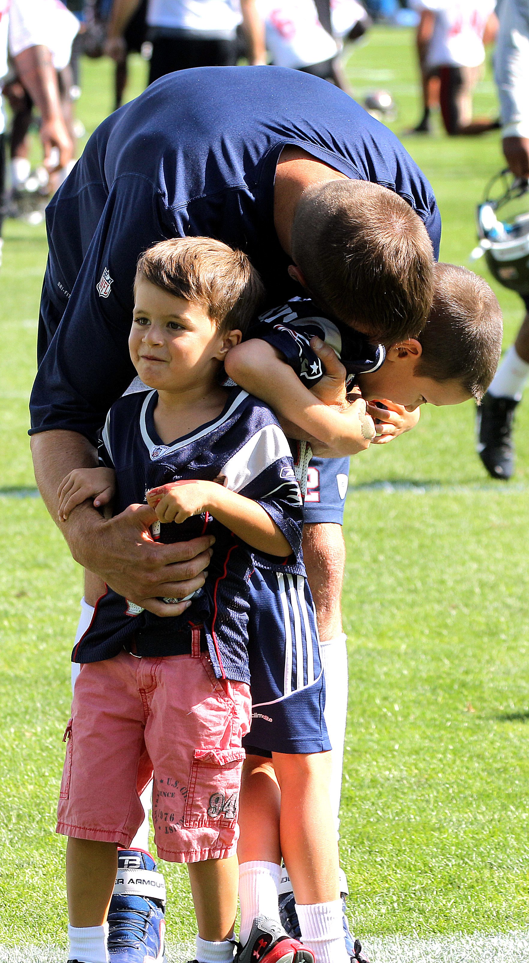 Tom Brady is greeted by his sons, Benjamin, left, and Jack as the New England Patriots end their last practice on Thursday, August 15, 2013, before the Friday exhibition game against the Tampa Bay Buccaneer | Source: Getty Images 