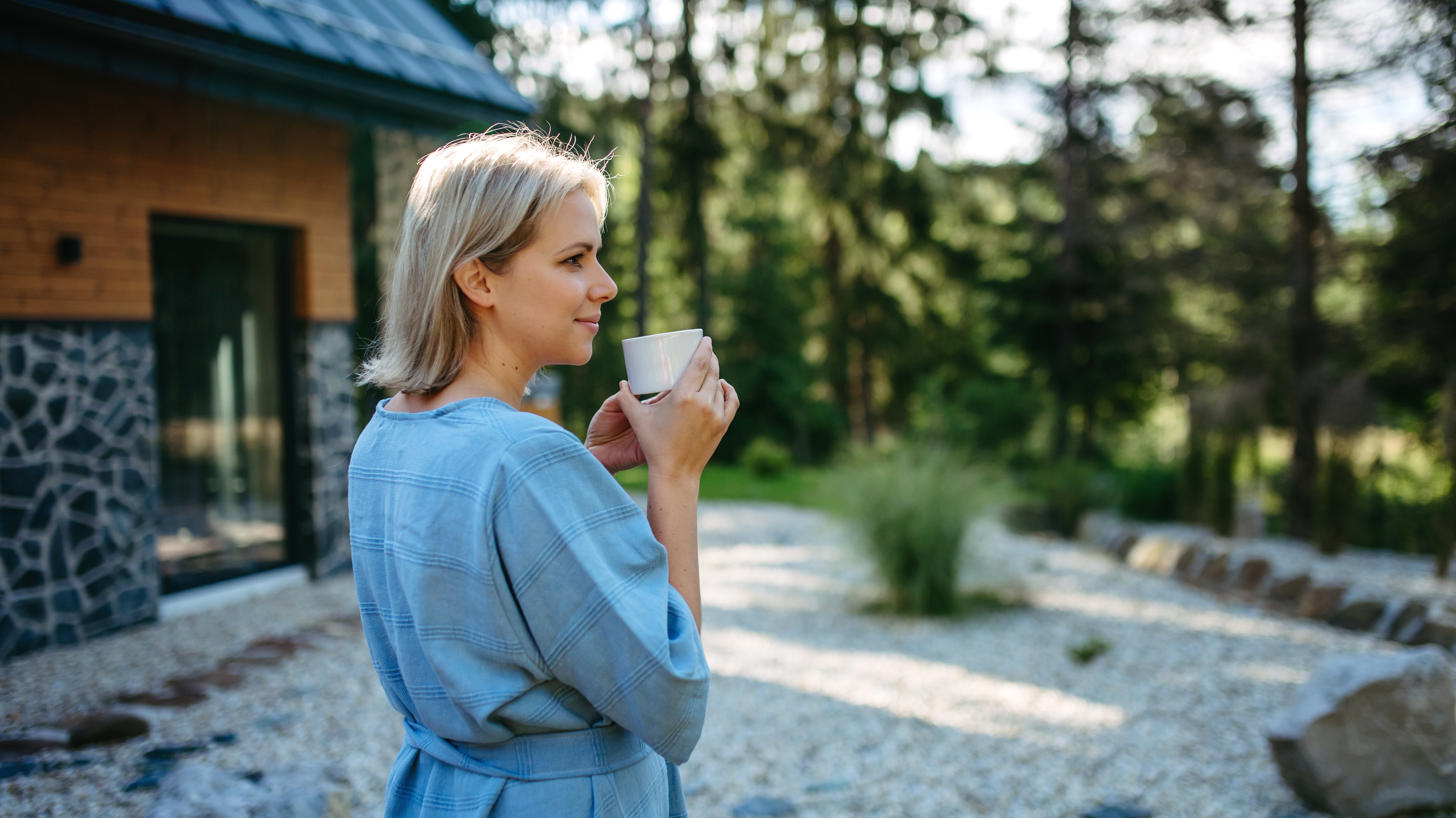 A woman enjoying a cup of coffee in a garden outside her home | Source: Shutterstock