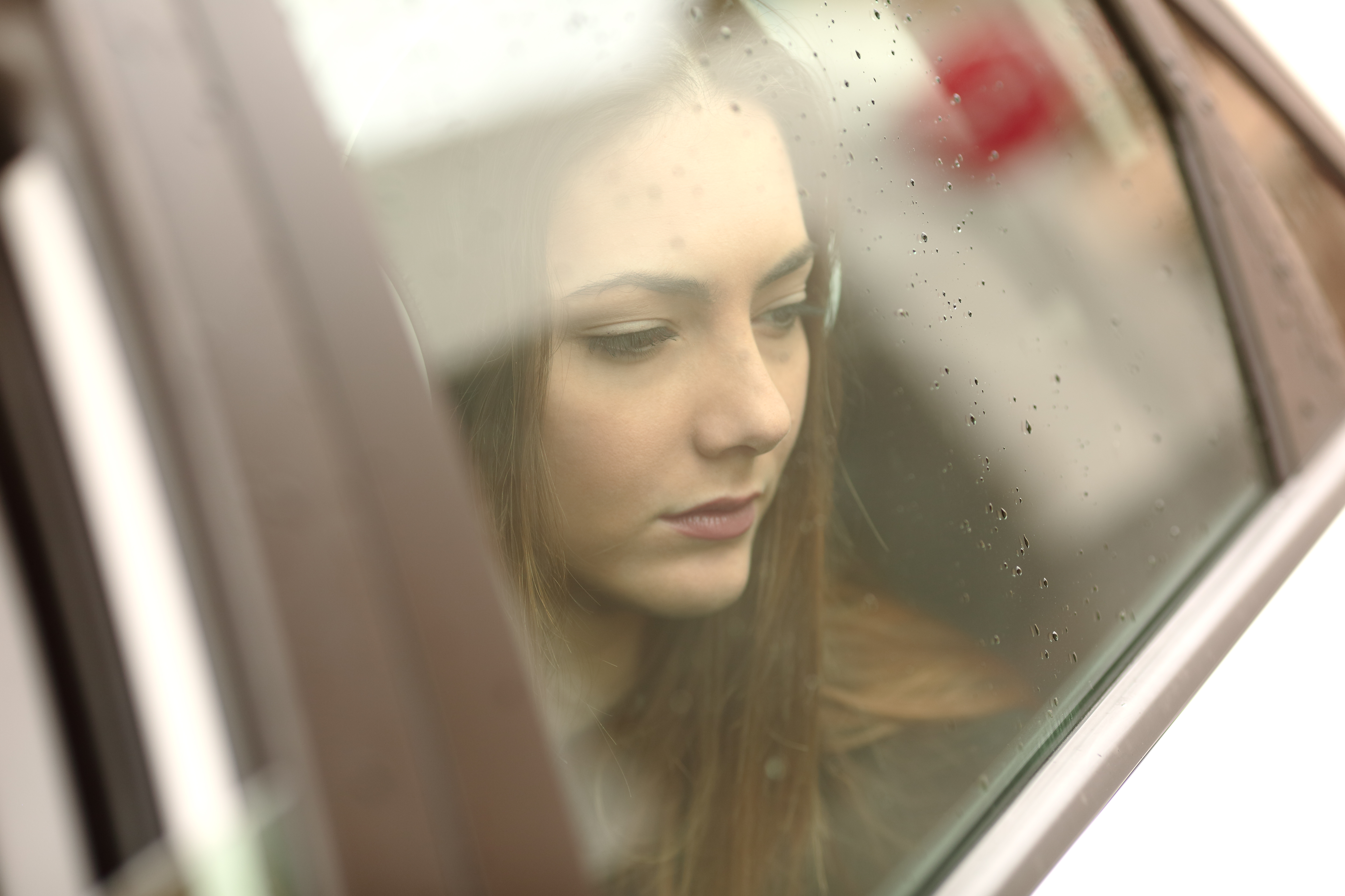 Young girl is sitting in the car and looking through the window | Source: Shutterstock.com
