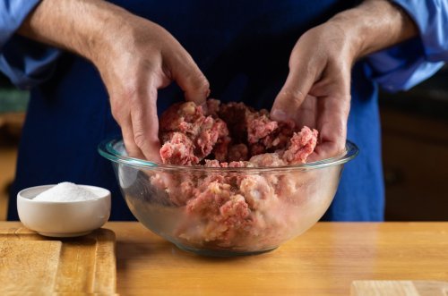Hands of a home cook mixing fresh ground meat. | Source: Shutterstock