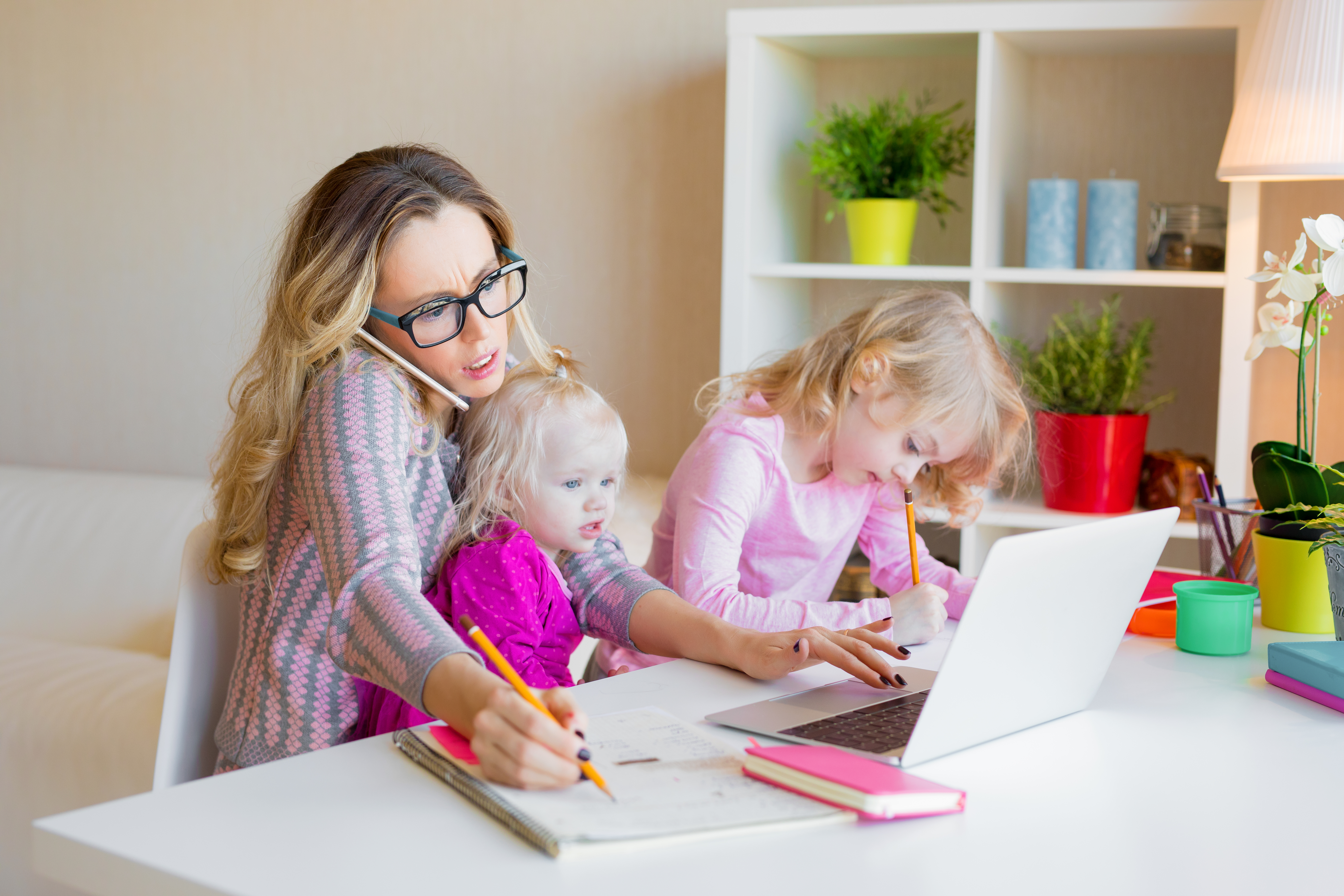 A woman working with two children on her lap | Source: Shutterstock