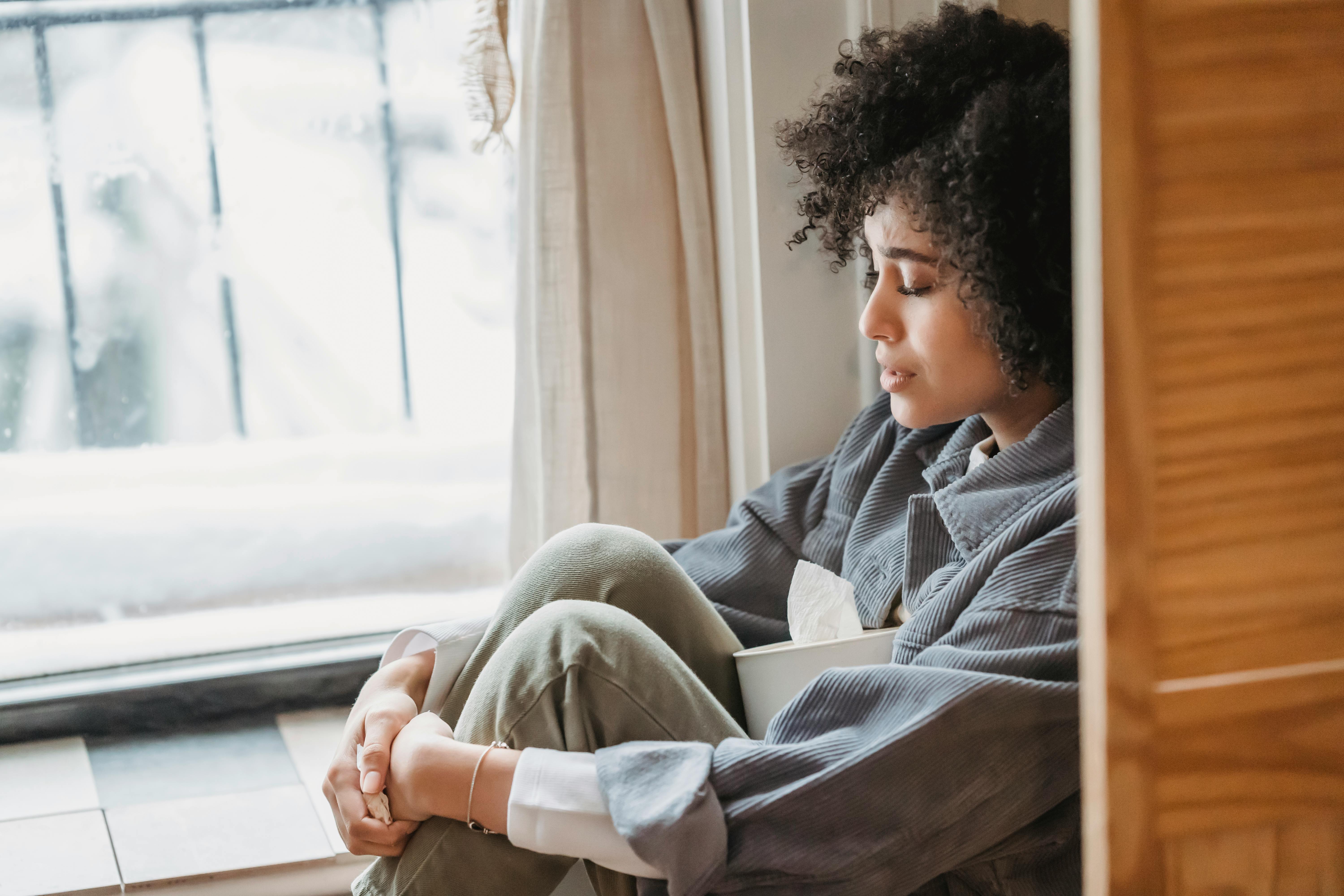 An emotional woman sitting curled up in a corner | Source: Pexels