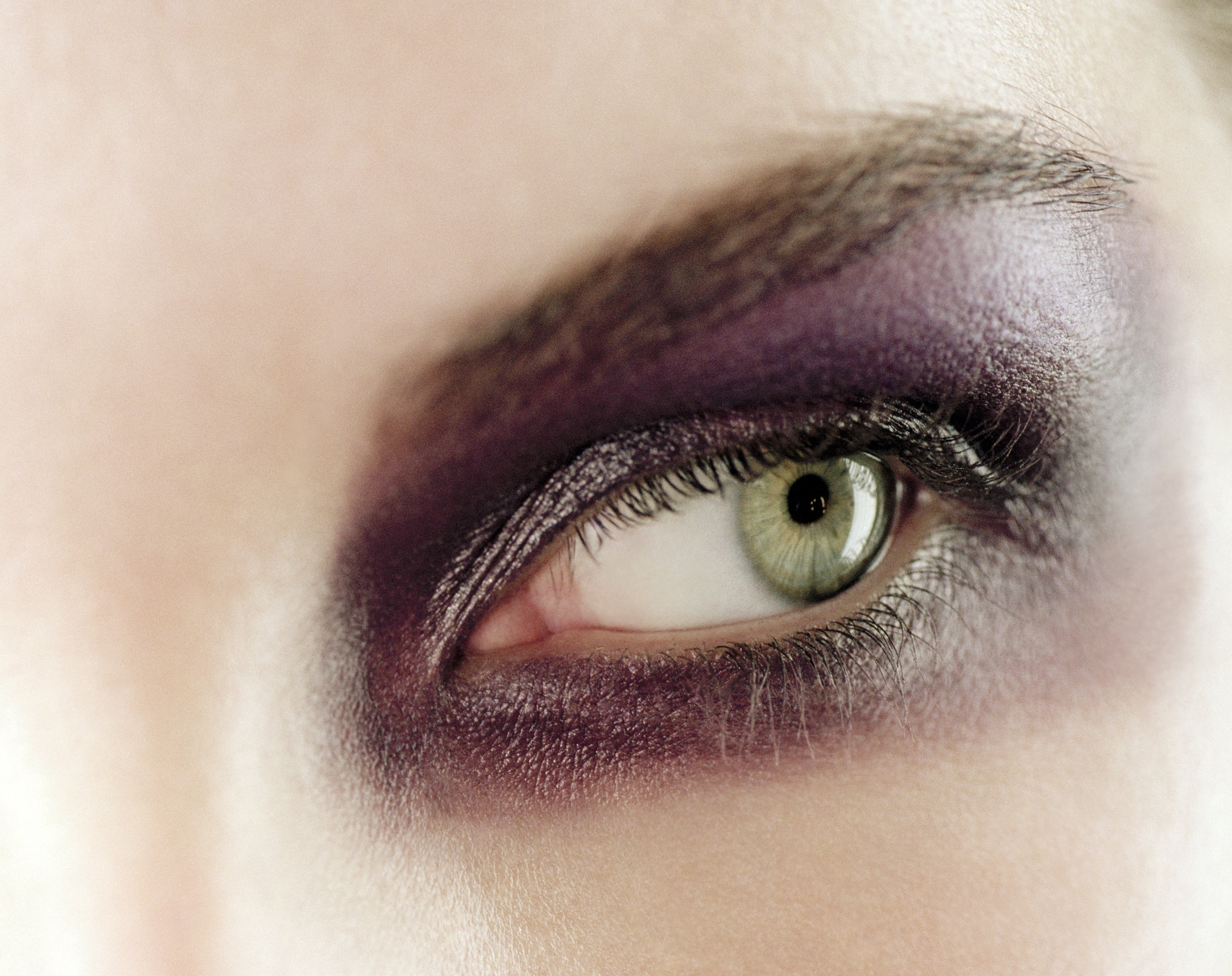 Young green-eyed woman wearing purple eyeshadow. | Source: Getty Images