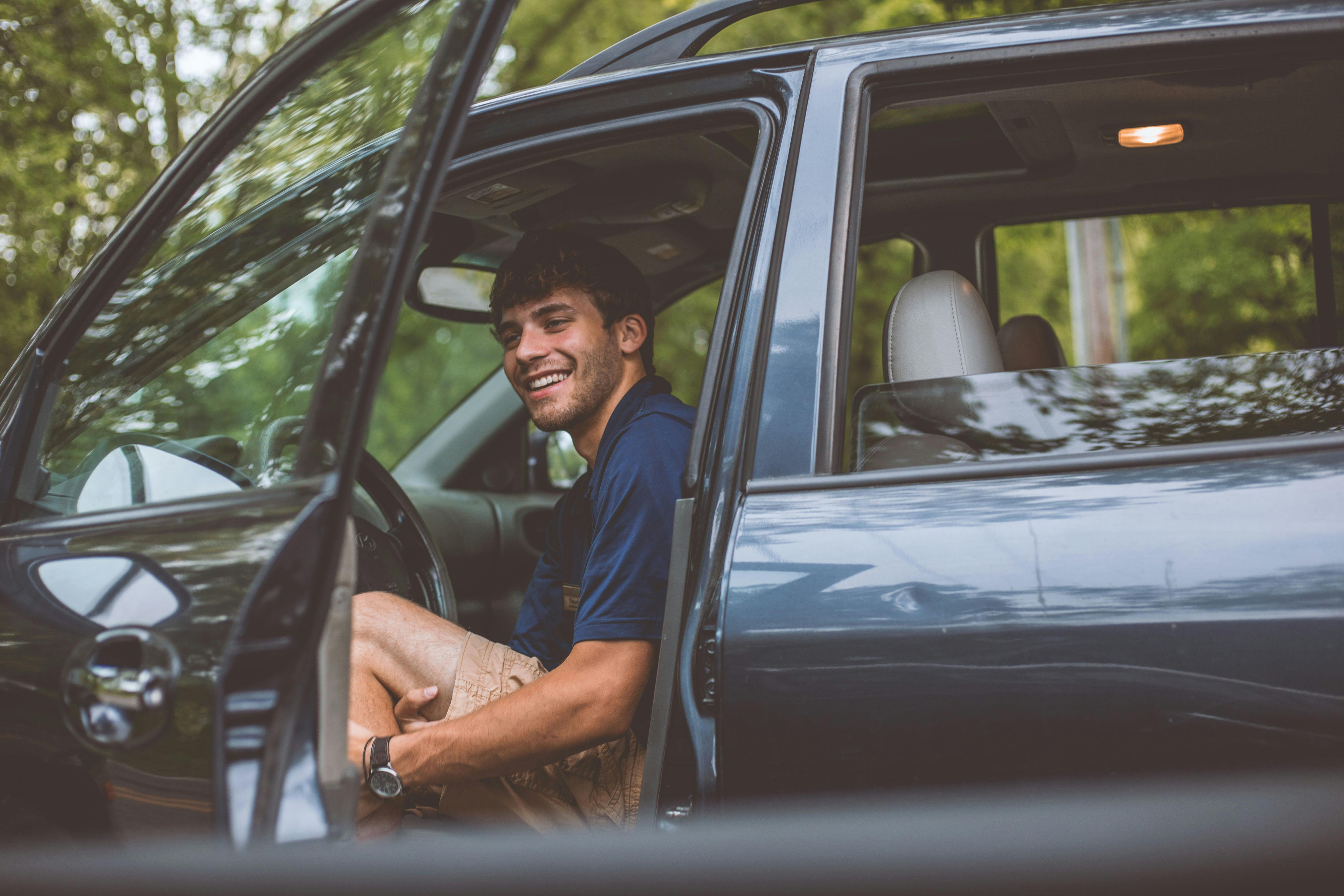 A ride-hailing service driver opens his door to welcome a passenger | Source: Pexels