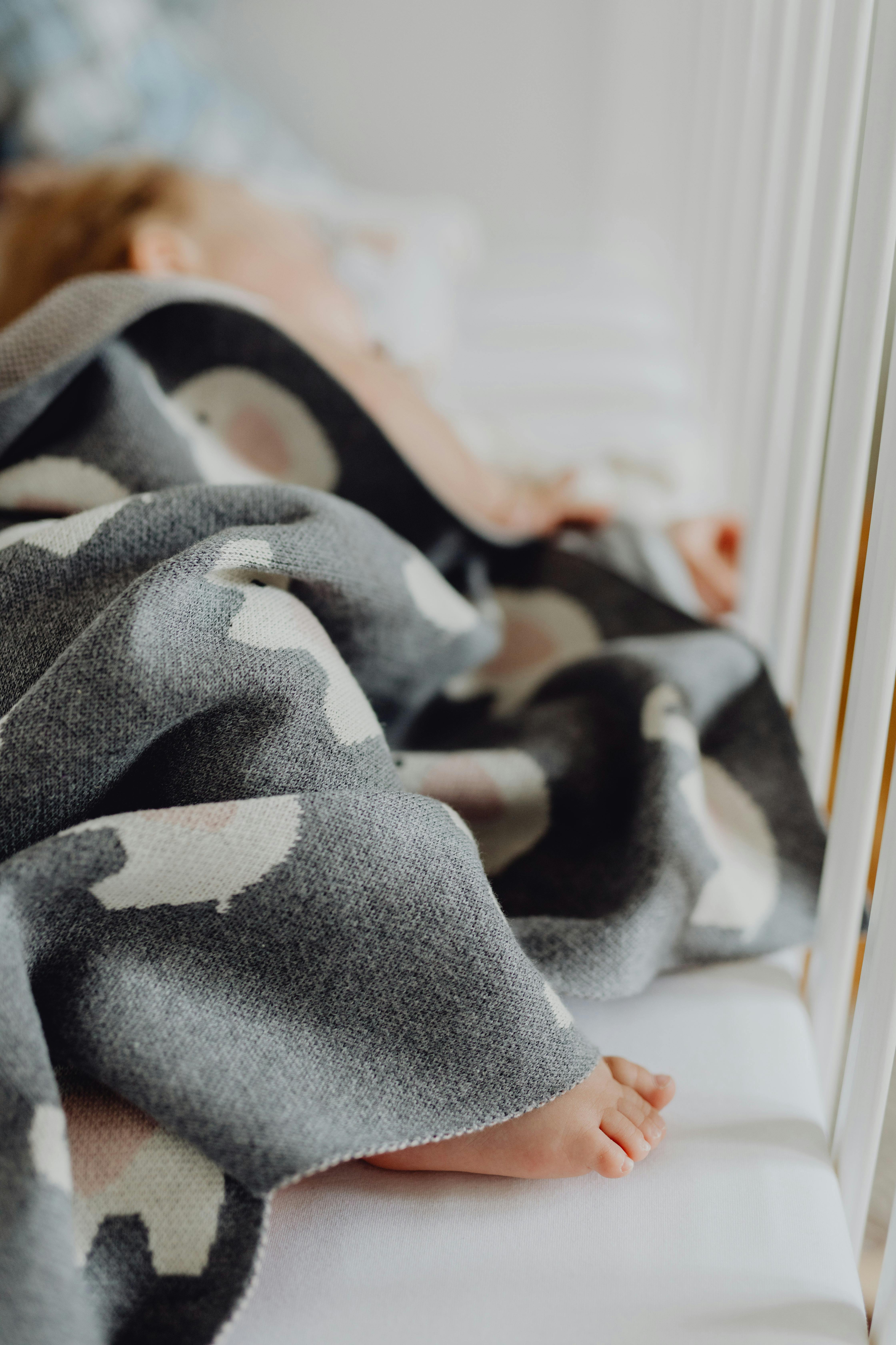 A baby sleeping in a crib with a blanket | Source: Pexels