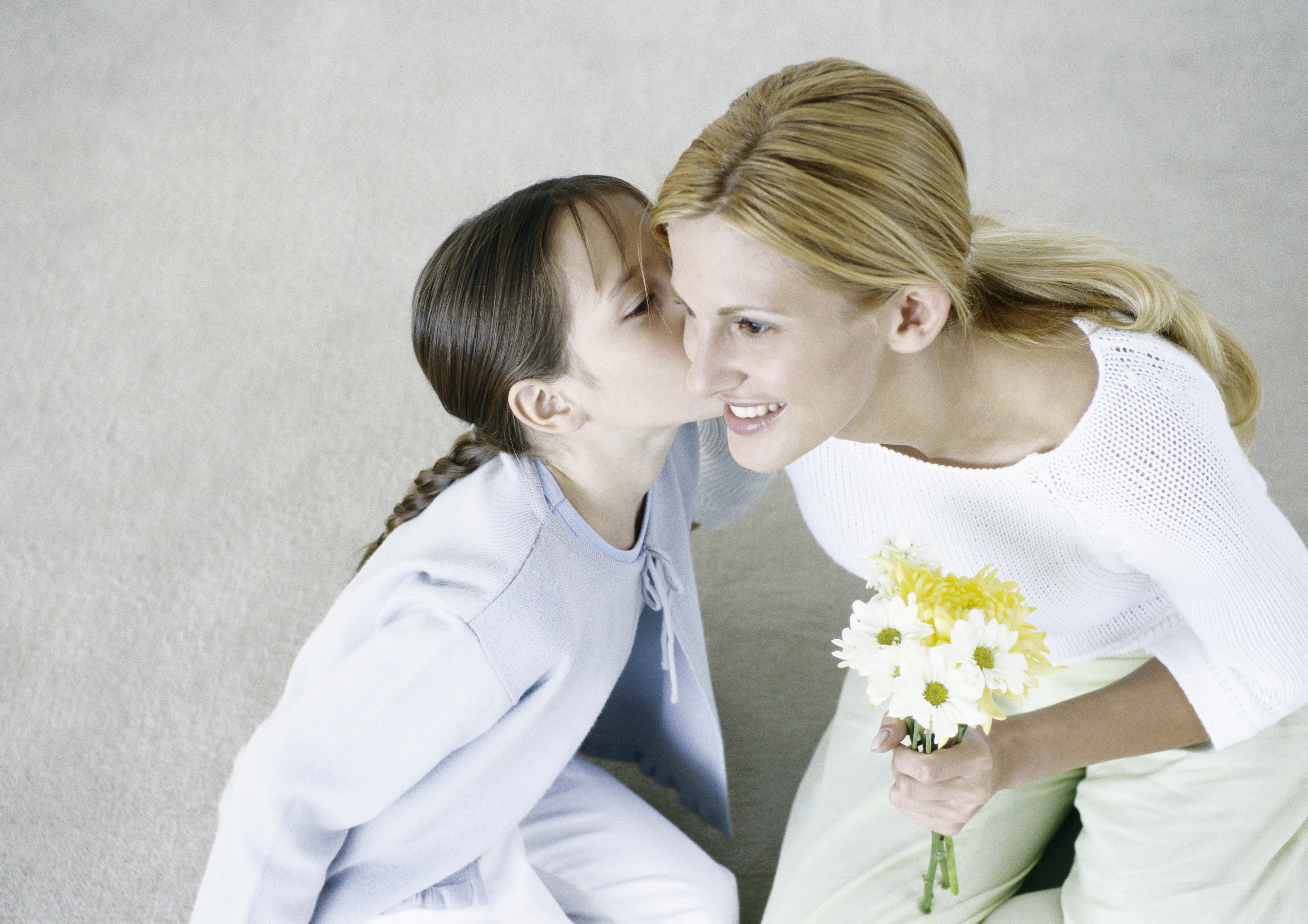 Woman holding bouquet of flowers, girl kissing her cheek | Source: Getty Images