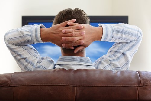 A man relaxing watching television. | Source: Shutterstock.