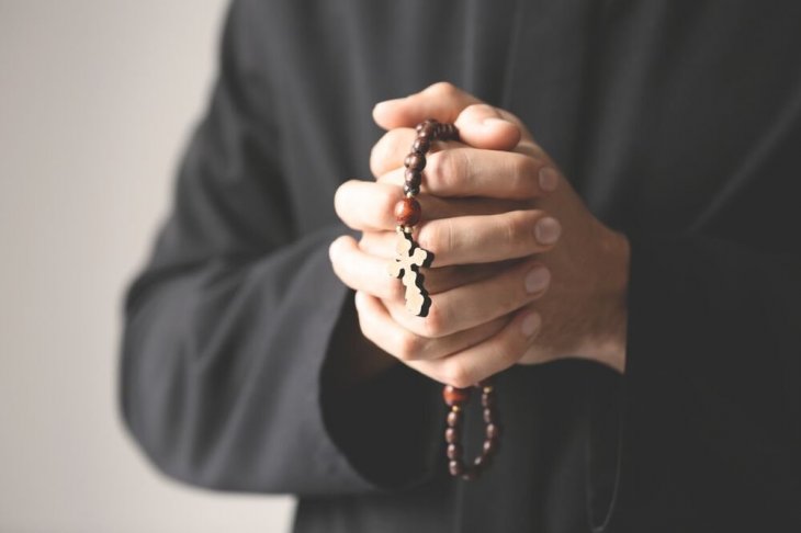 Sacerdote sosteniendo un rosario entre sus puños cerrados. | Imagen: Shutterstock Sacerdote sosteniendo un rosario entre sus puños cerrados. | Imagen: Shutterstock