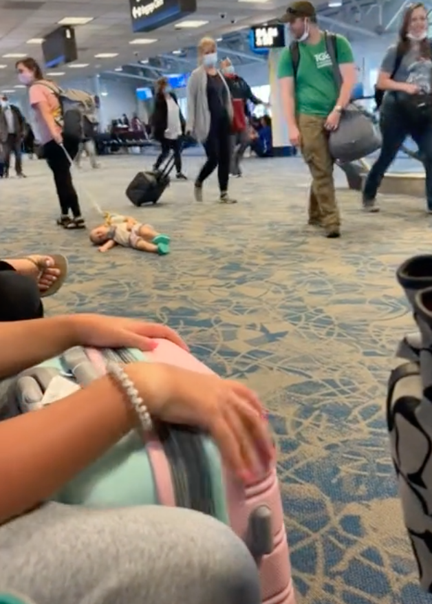 Eine Frau schleppt ein Kind durch den Flughafen. | Quelle: tiktok.com/cacadoodledoo83