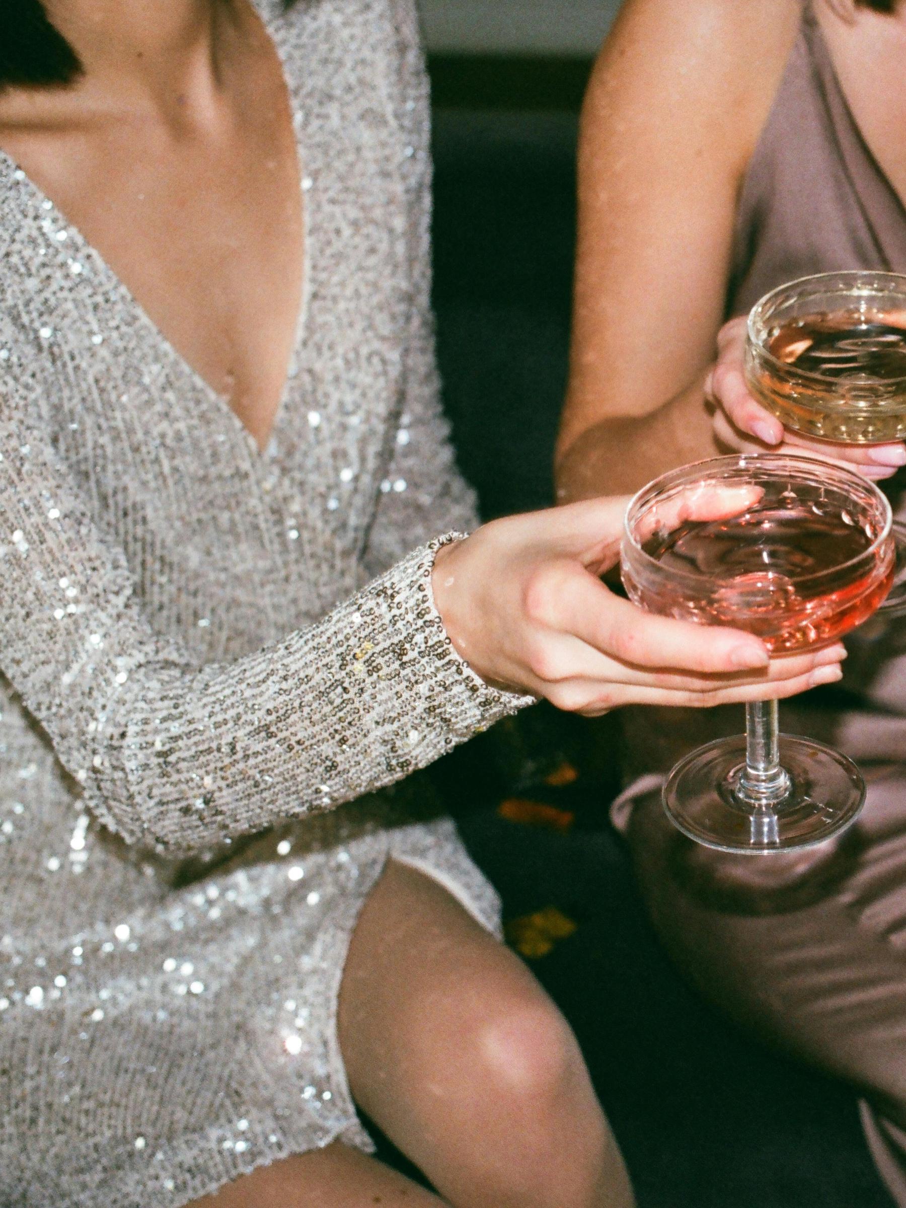 A woman in a dazzling dress holds a glass of champagne | Source: Pexels