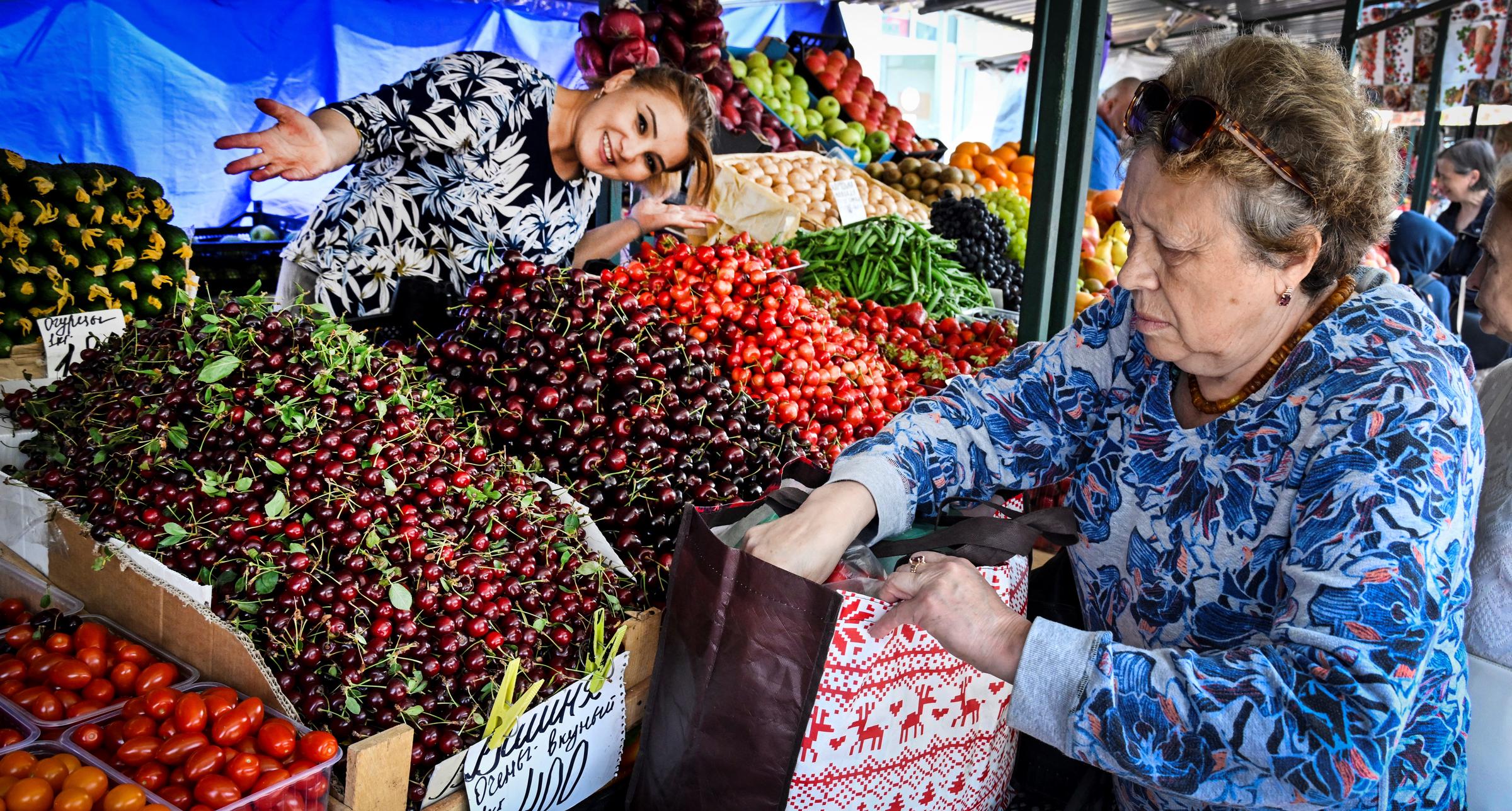A vendor offers cherries and vegetables at a market | Source: Getty Images