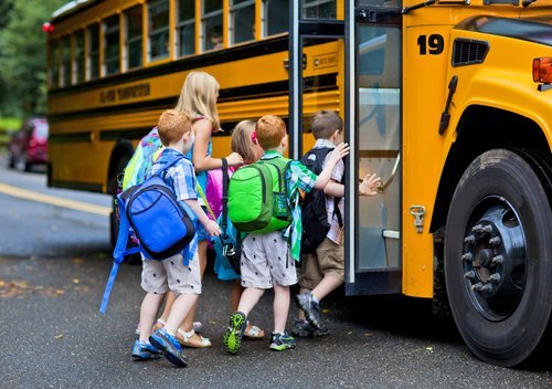 A group of young children getting on the schoolbus | Photo: Shutterstock.com