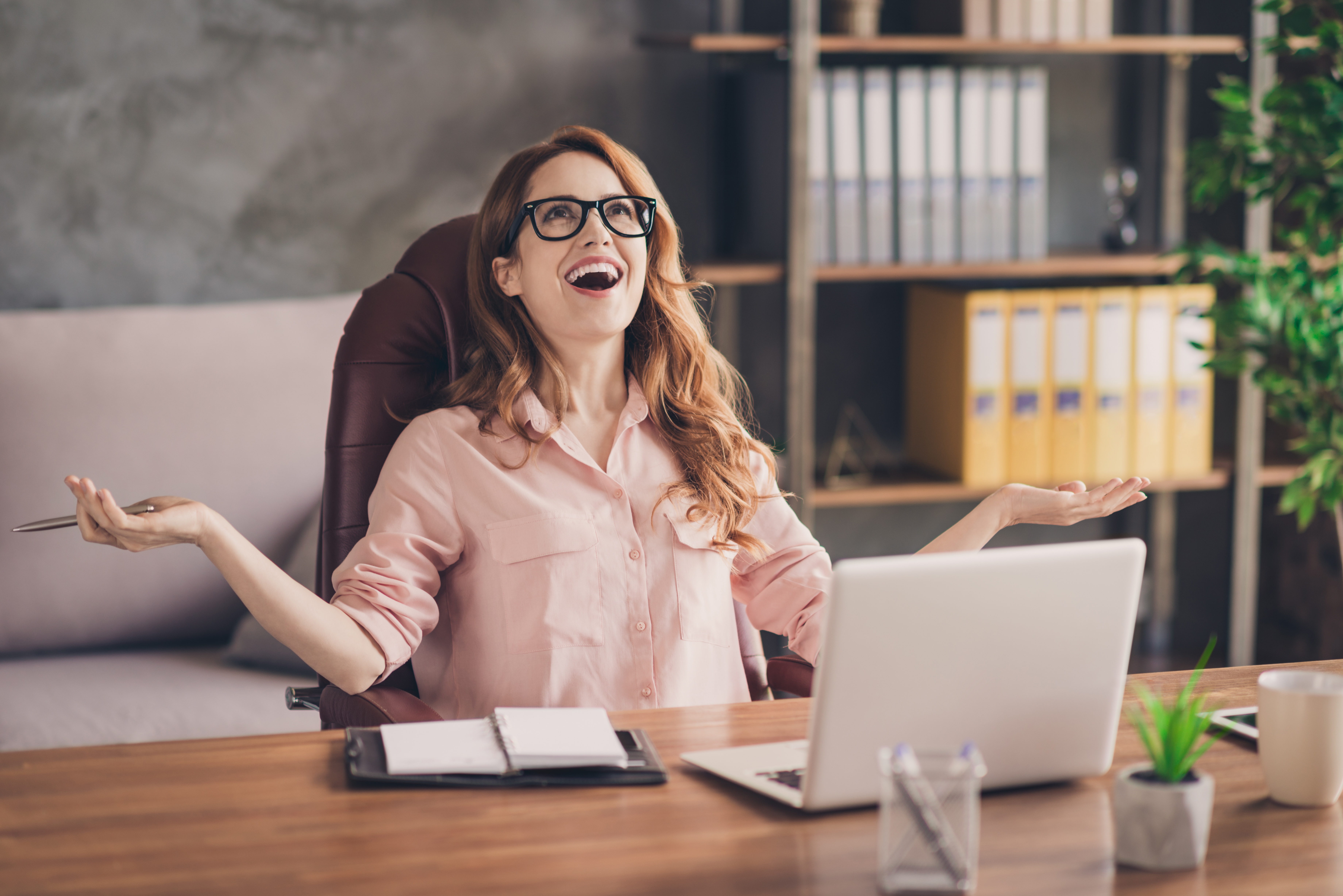 Close up photo beautiful she her business lady hand arm head raised up laugh laughter big salary income earnings genius startup notebook table sit office chair wearing specs formal-wear shirt | Source: Getty Images