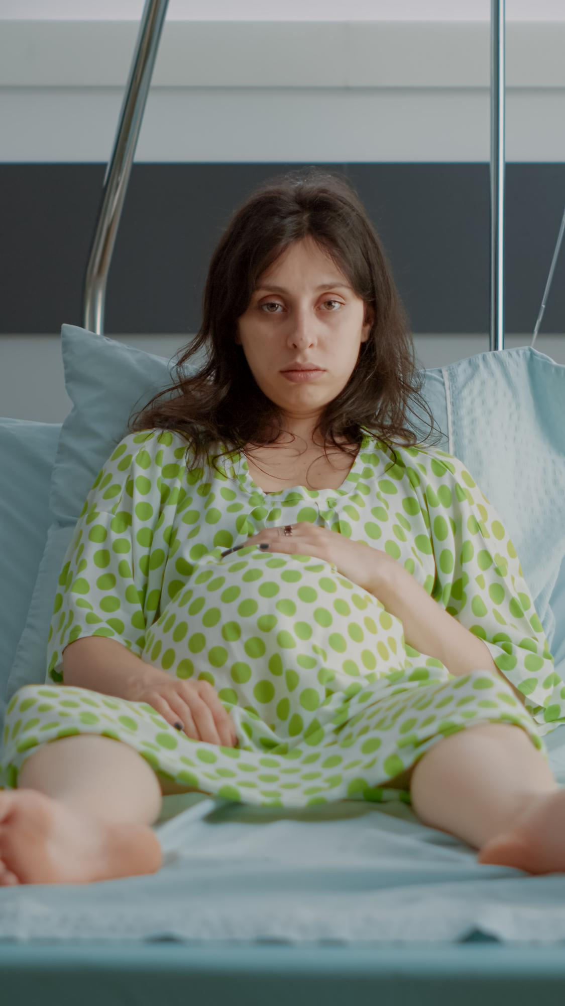 An unhappy pregnant woman lying in a hospital bed | Source: Freepik