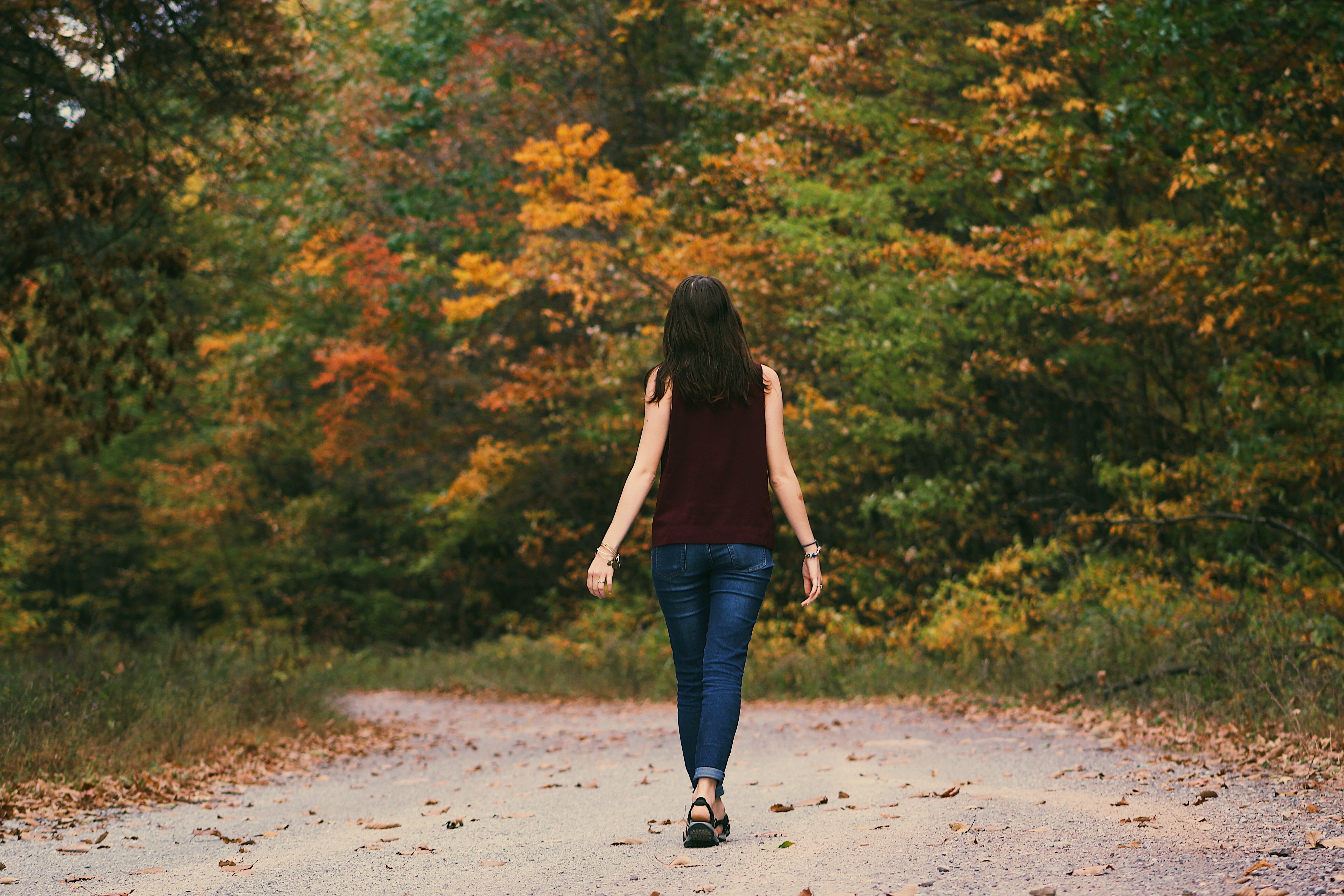 Una joven mujer camina por una via de tierra. | Foto: Pexels