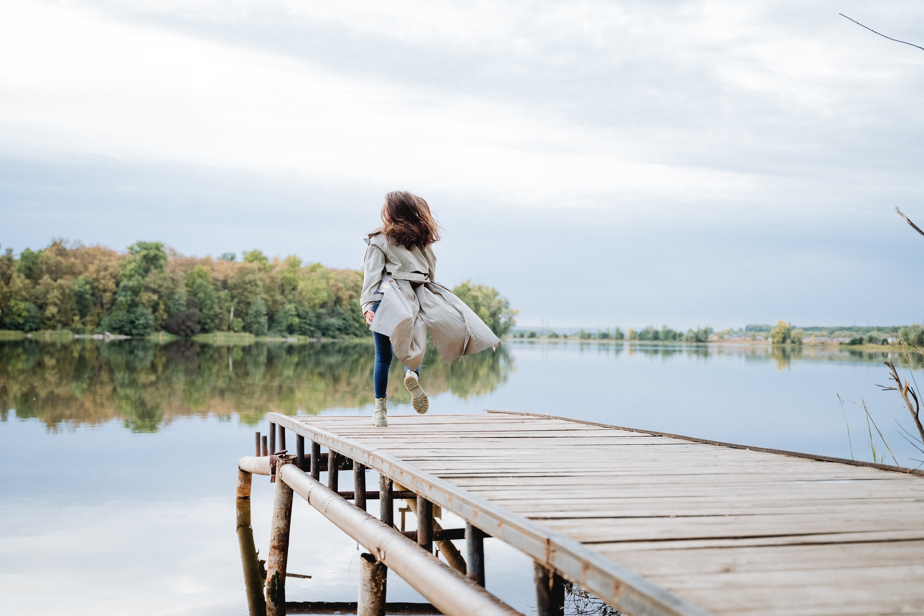 A girl in a raincoat runs across a bridge | Source: Shutterstock