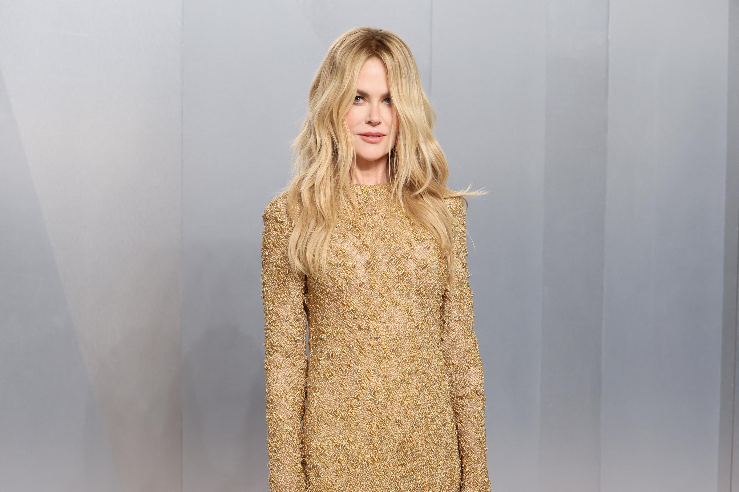 Nicole Kidman stands against a sleek pale backdrop at the event, showcasing the full silhouette of her shimmering long-sleeved dress. | Source: Getty Images