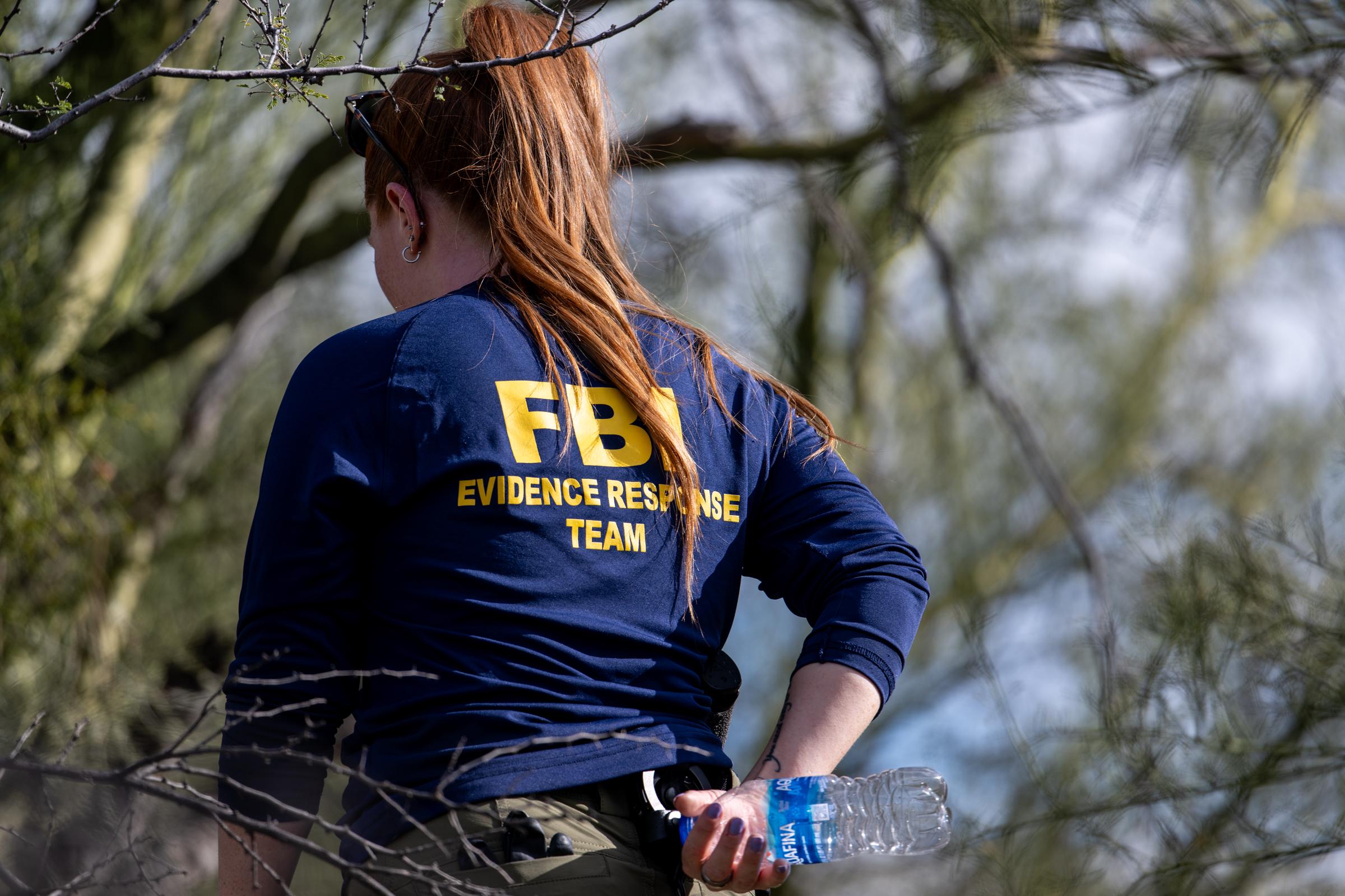 An FBI agent searches the area around Nancy Guthrie's residence on February 11, 2026 | Source: Getty Images