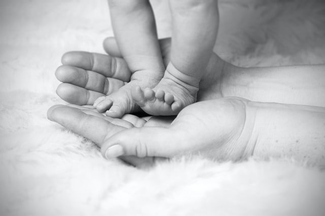 Les pieds d’un bébé sur les paumes de la main d'une personne | Source : Unsplash