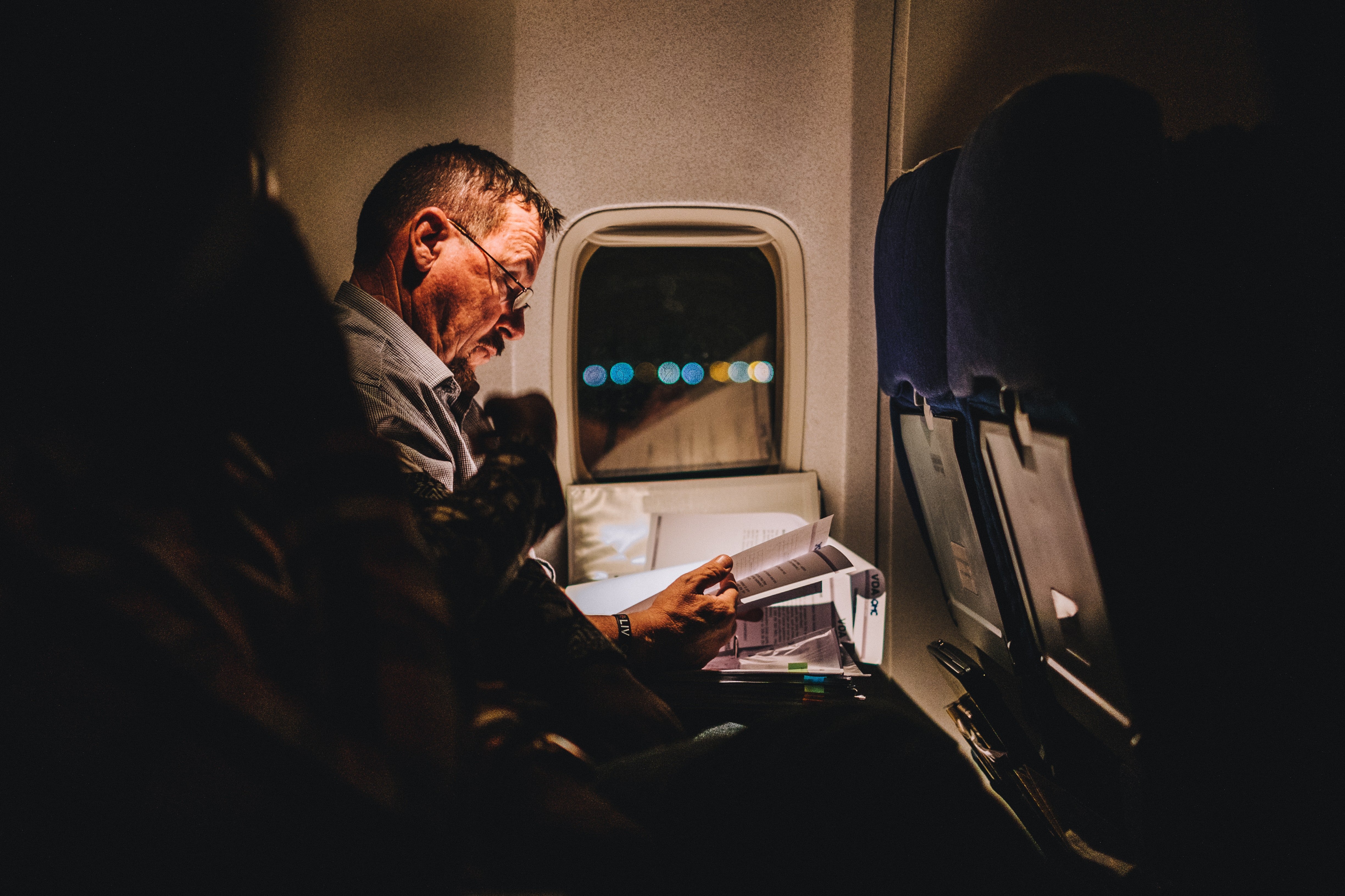 Hombre mayor esta leyendo en el asiento de un vuelo aéreo. | Foto: Unsplash