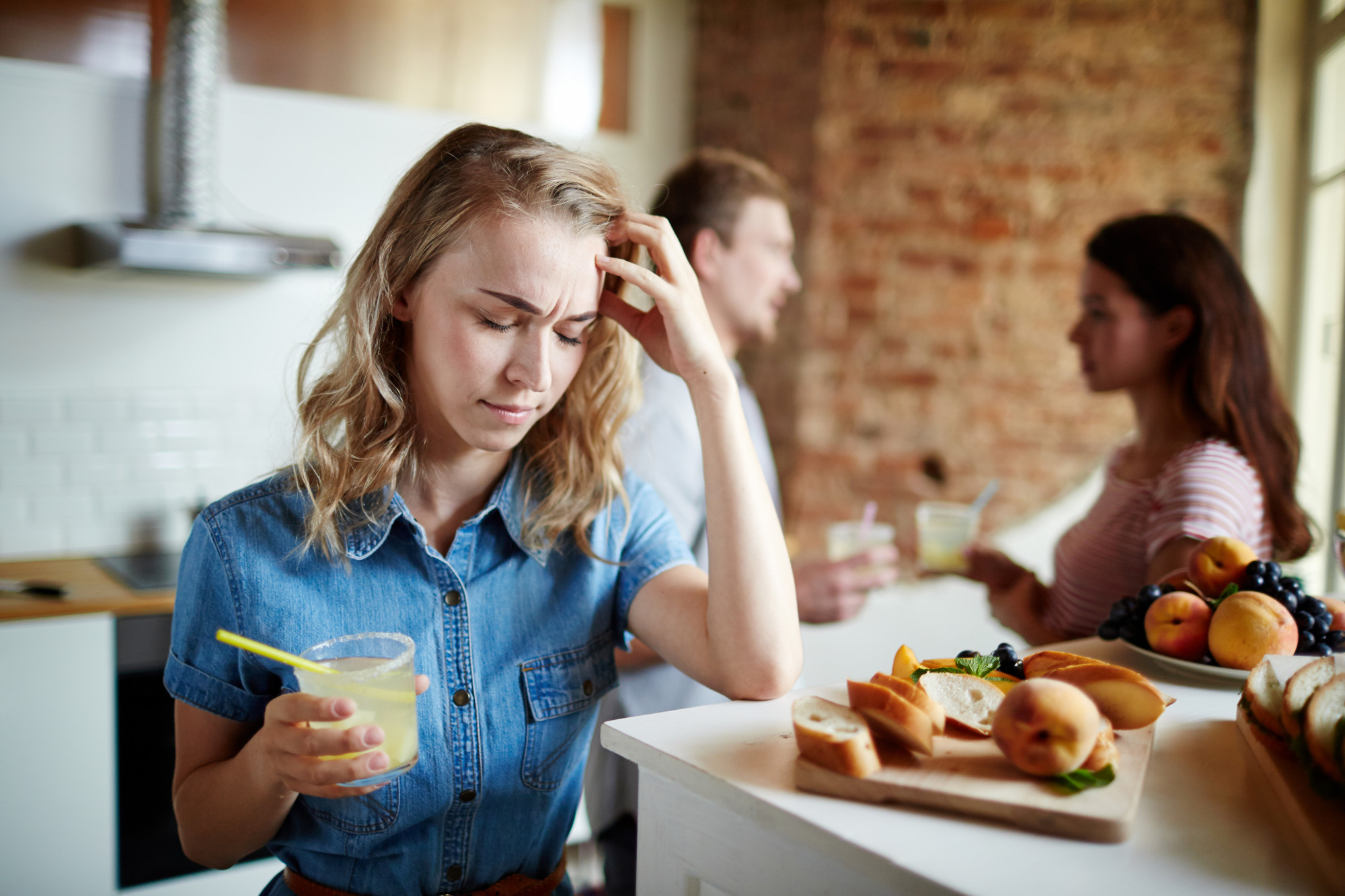 A distressed woman in the foreground while a couple talks in the background | Source: Freepik