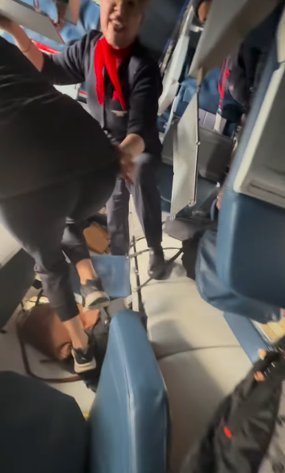 Inside the plane, a flight attendant assists passengers as they navigate through overturned seats and scattered debris, from a video dated February 18, 2025 | Source: Instagram.com/eggxit