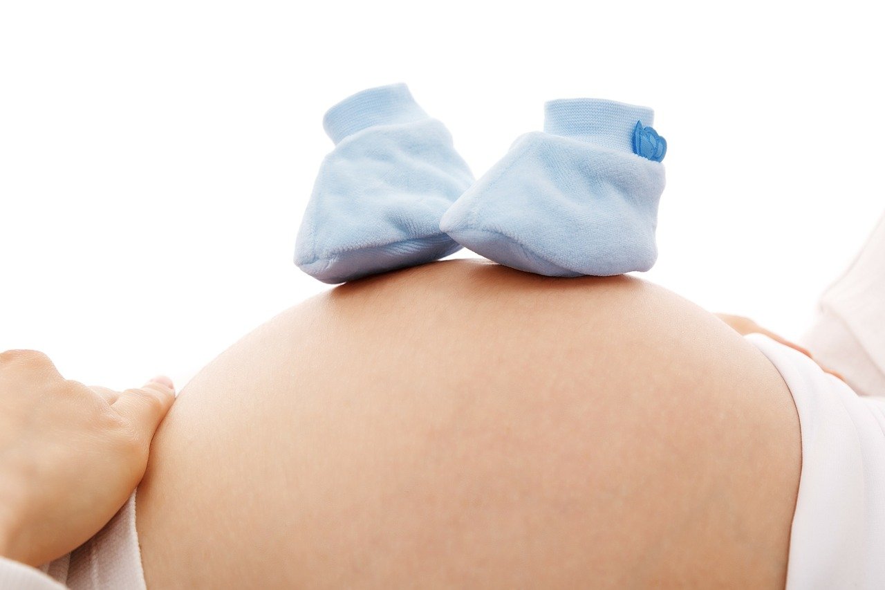 Mujer embarazada con unos escarpines en su barriga. | Foto: Pixabay