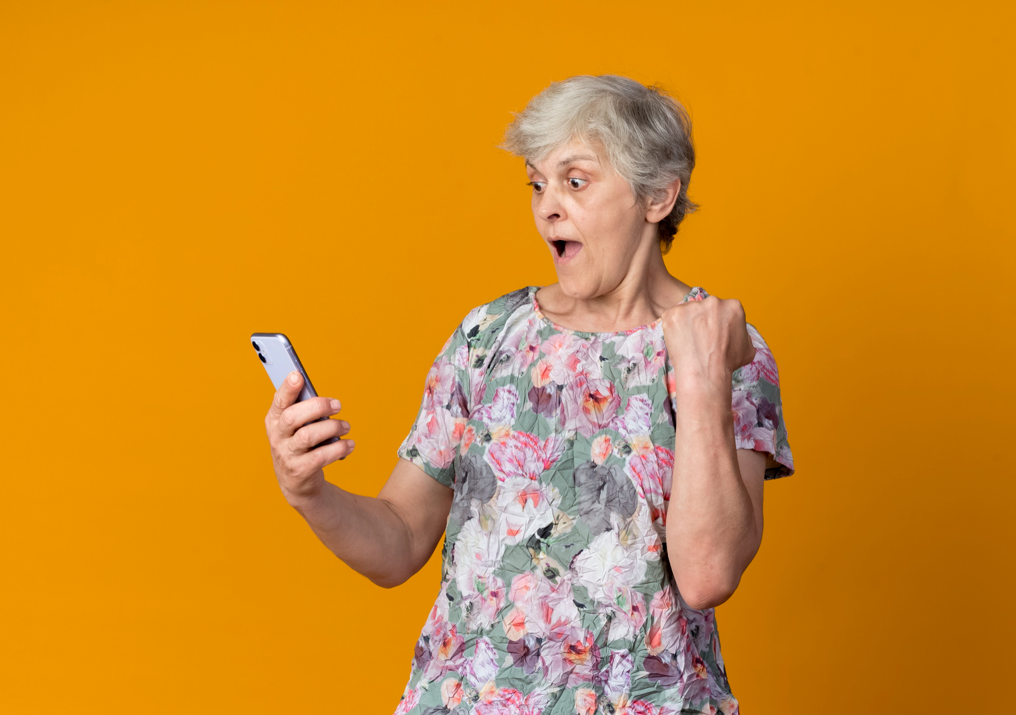An older woman reacting in shock while looking at her phone | Source: Freepik