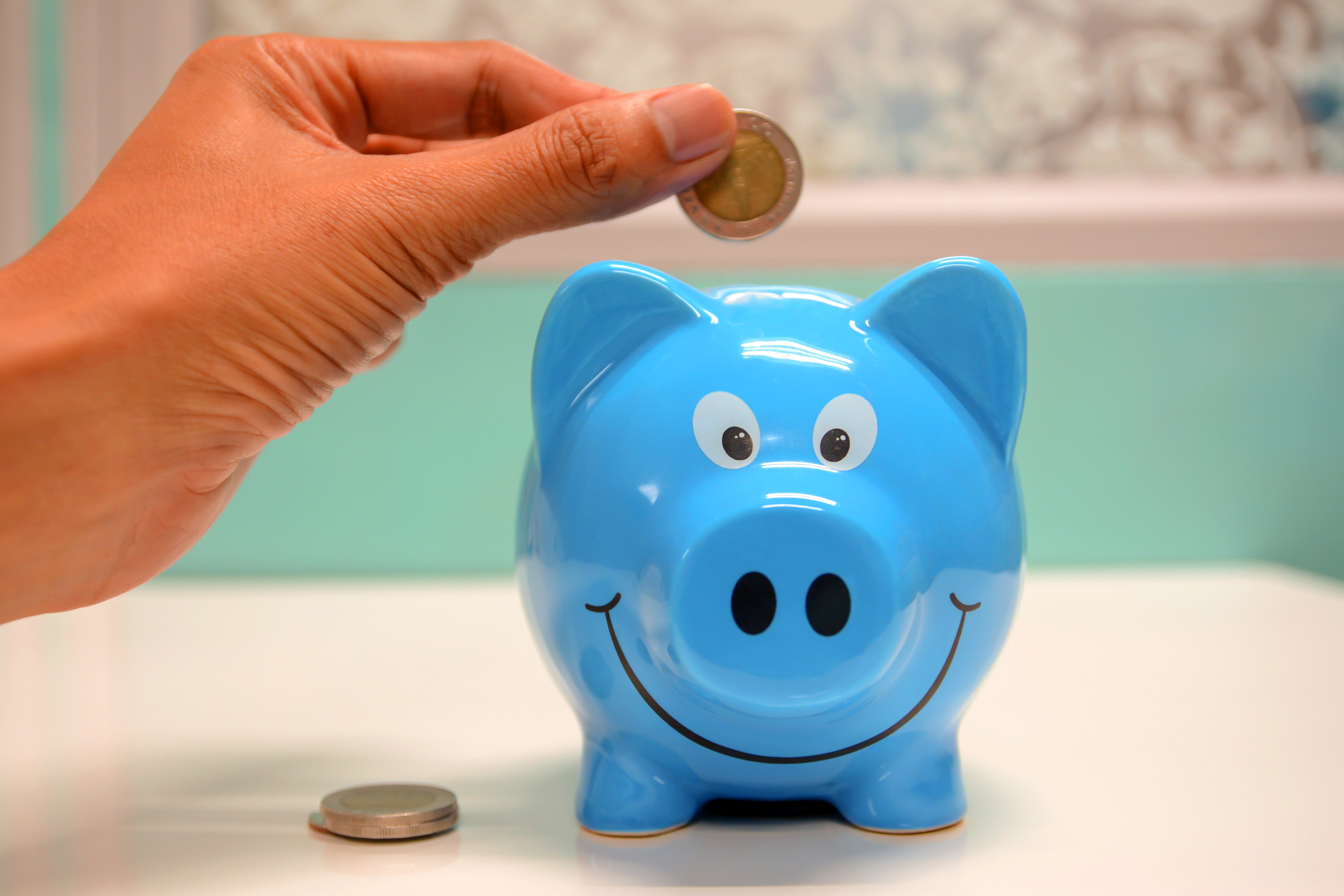 An individual putting money into a piggy bank. | Source: Pexels