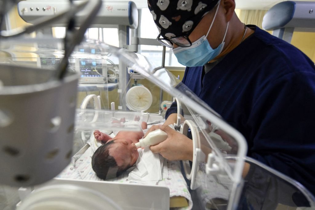 A medical staff member feeds a newborn baby in the paediatric ward on April 25, 2021 | Photo: Getty Images