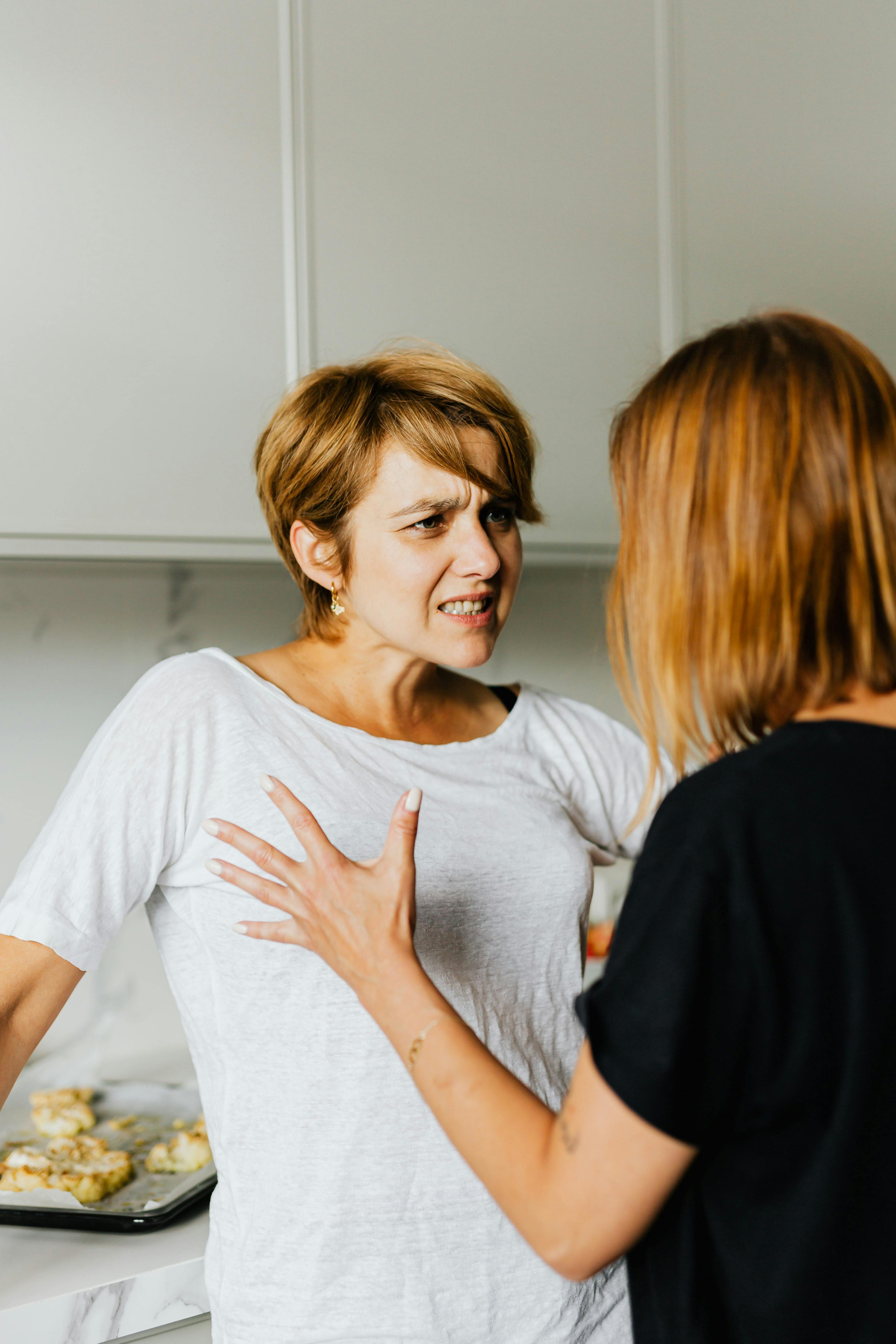 A woman looking upset while listening to another one talk | Source: Pexels