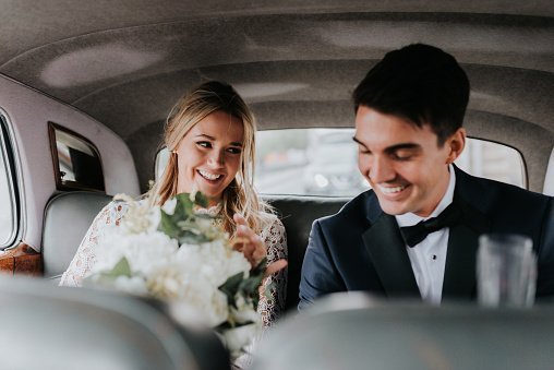 Bride and bridegroom in backseat of car | Photo: Getty Images