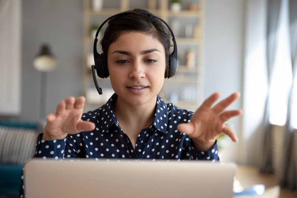 Young Indian businesswoman wearing wireless headsets while talking to someone else on a video call | Photo: Shutterstock/fizkes