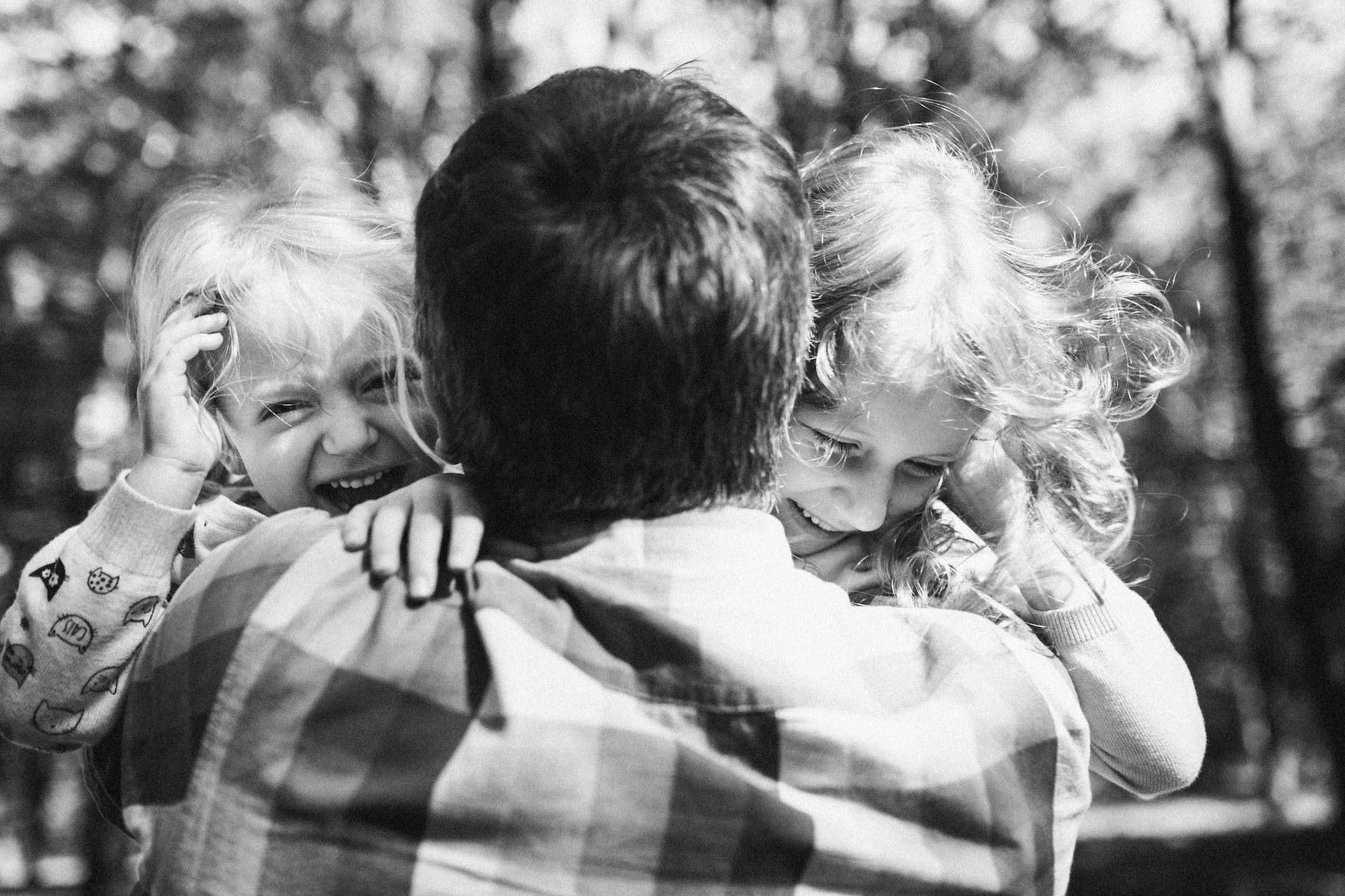 A father hugging his daughters | Source: Pexels
