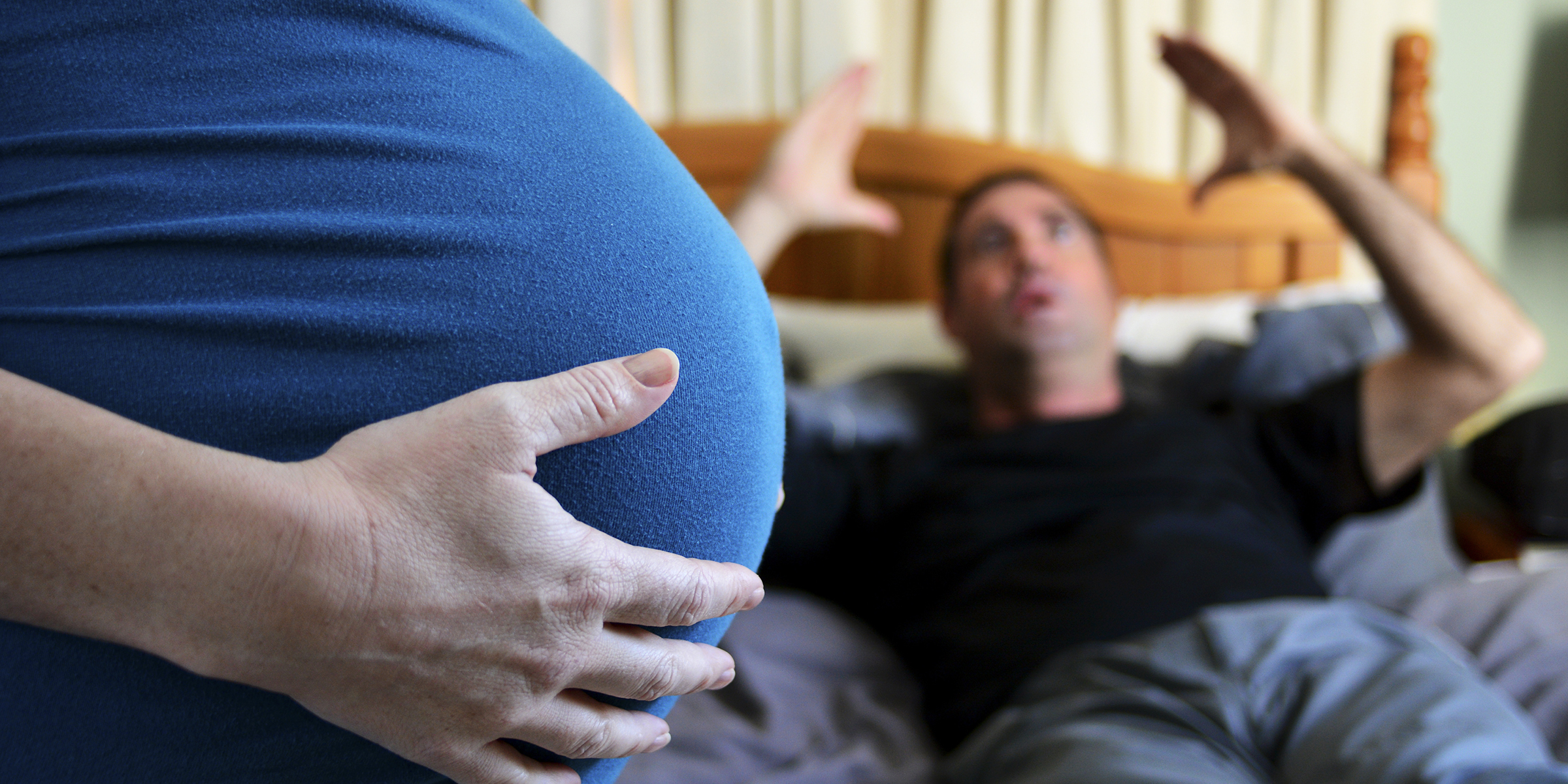 A pregnant woman with an angry man in the background | Source: Shutterstock