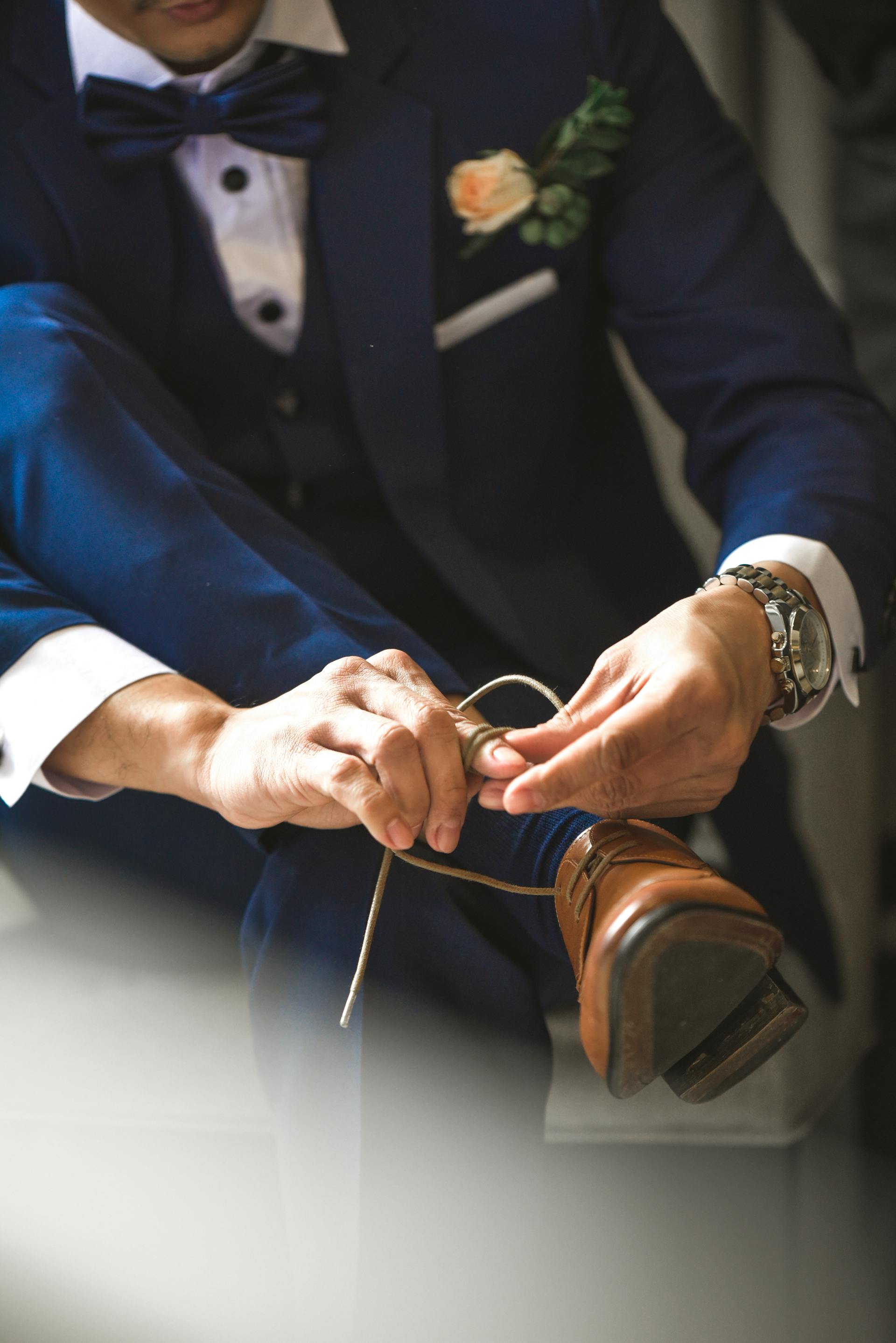 A groom tying his shoelaces | Source: Pexels