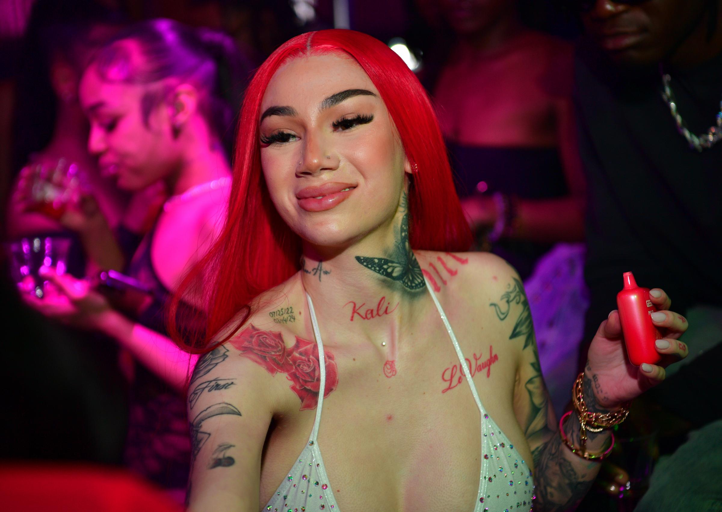 Bhad Bhabie, now 22, lit up the room at Magic City in Atlanta with fiery red hair, dramatic lashes, and a plunging rhinestone halter top that showed off her heavily inked skin. With bold brows, glossy lips, and a confident pose, she radiated unfiltered energy — owning the spotlight with a look that was brash, bold, and unmistakably hers.