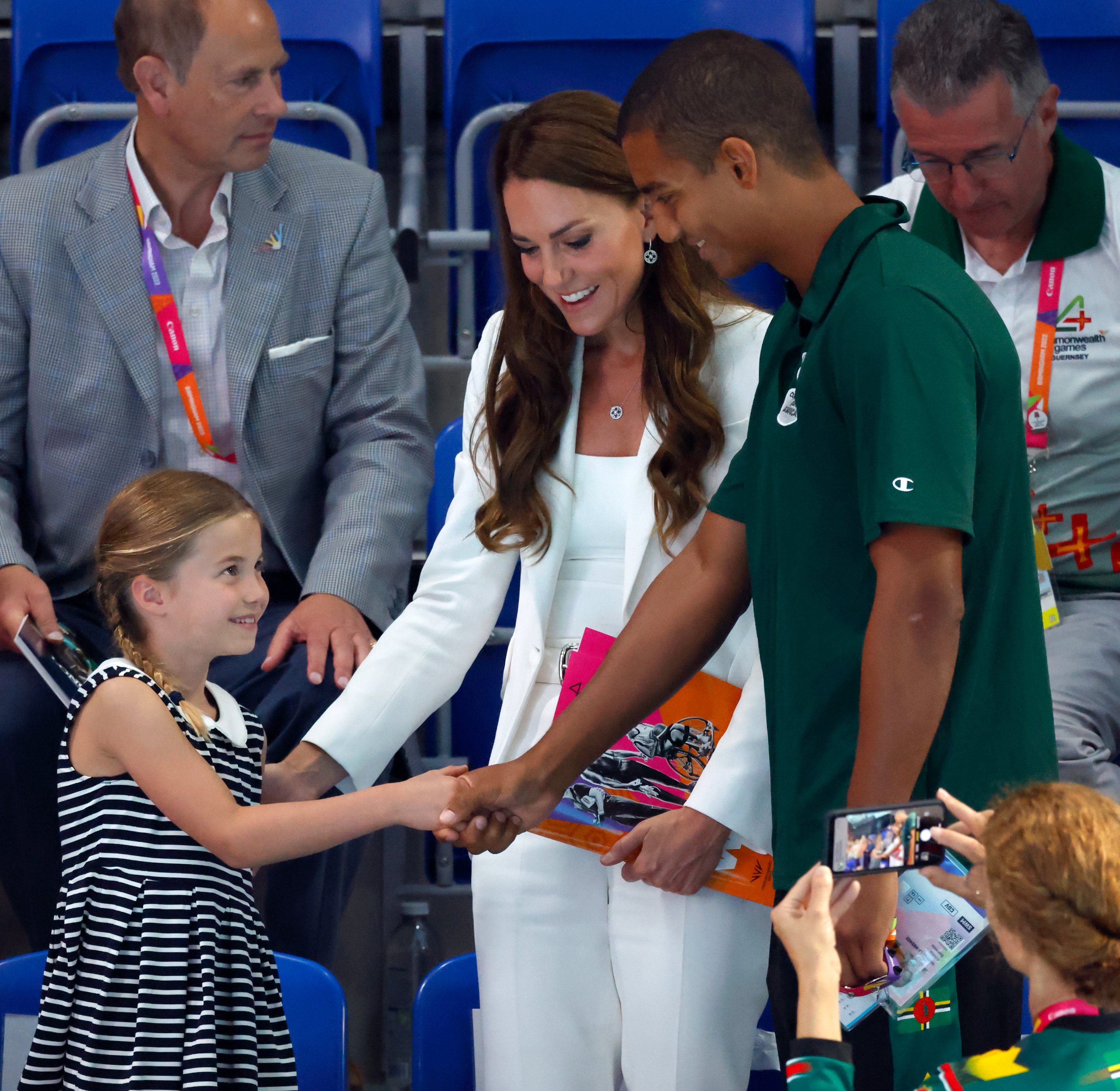 Kate Middleton and Princess Charlotte shaking hands with swimmer Warren Lawrence in Birmingham 2022. | Source: Getty Images