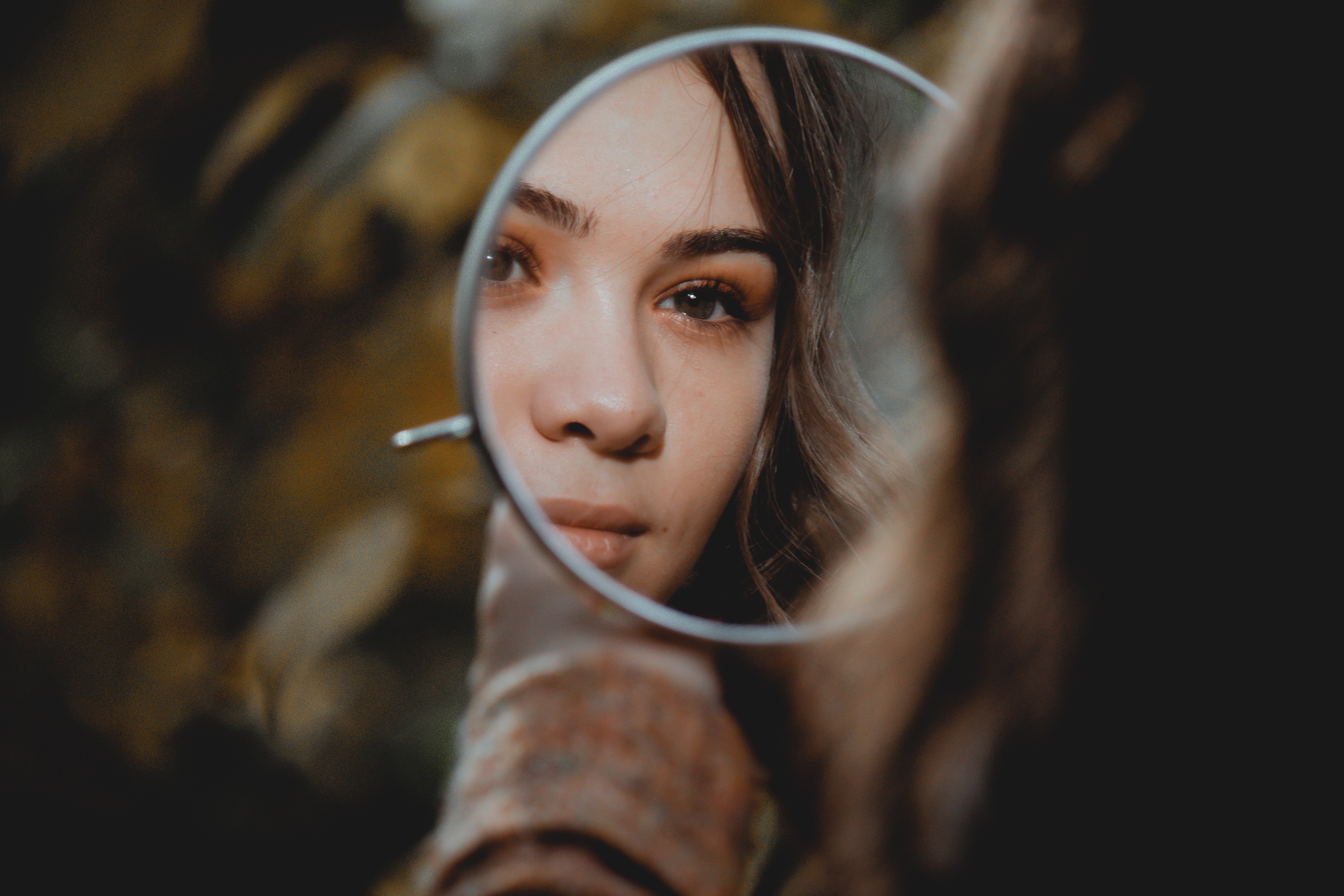 A woman looking in a mirror.│Source: Unsplash