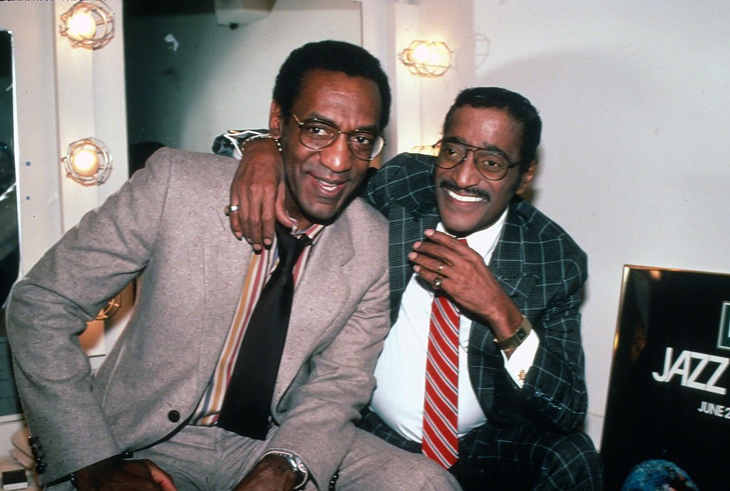 Sammy Davis Jr. embrace Bill Cosby while sitting backstage in front of a mirror on January 1, 1971, New York City | Photo: Getty Images