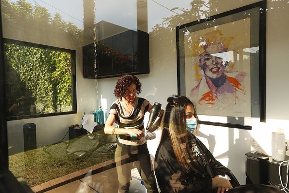 La coiffeuse Nourieh Daili, à gauche, coupe les cheveux de la cliente Roksana Koupaei, 21 ans.|Photo: Getty Images.