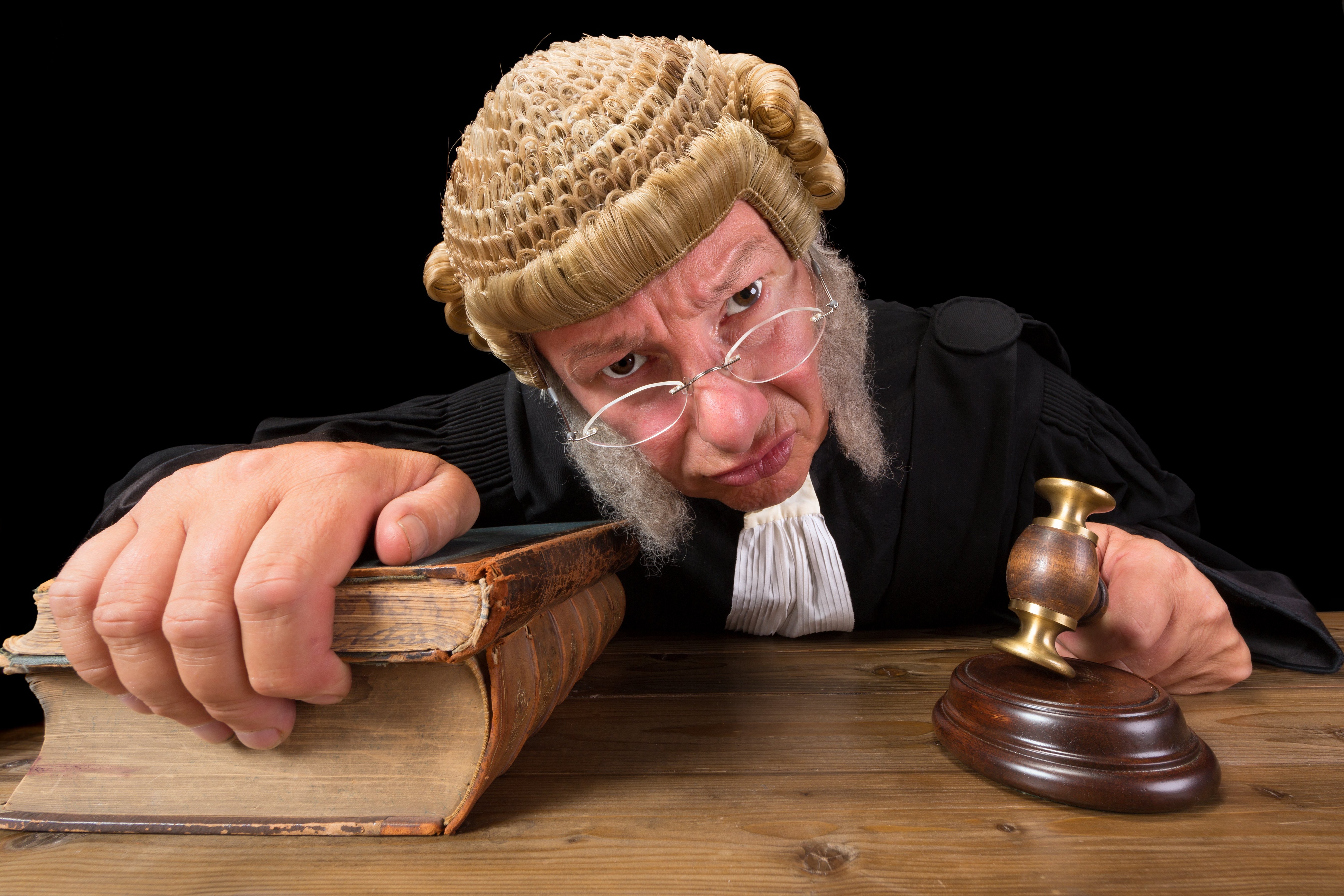 Angry judge with a hammer and a wig, holding legal tomes. Image credit: Shutterstock