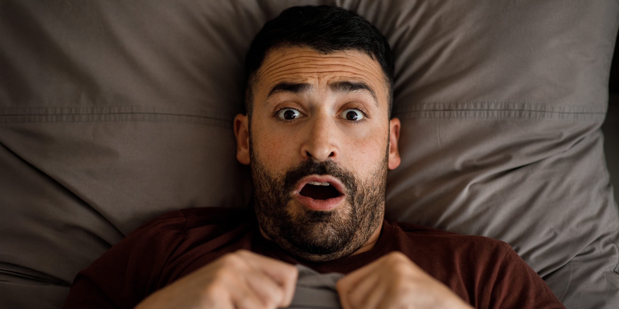 A shocked man in bed | Source: Shutterstock