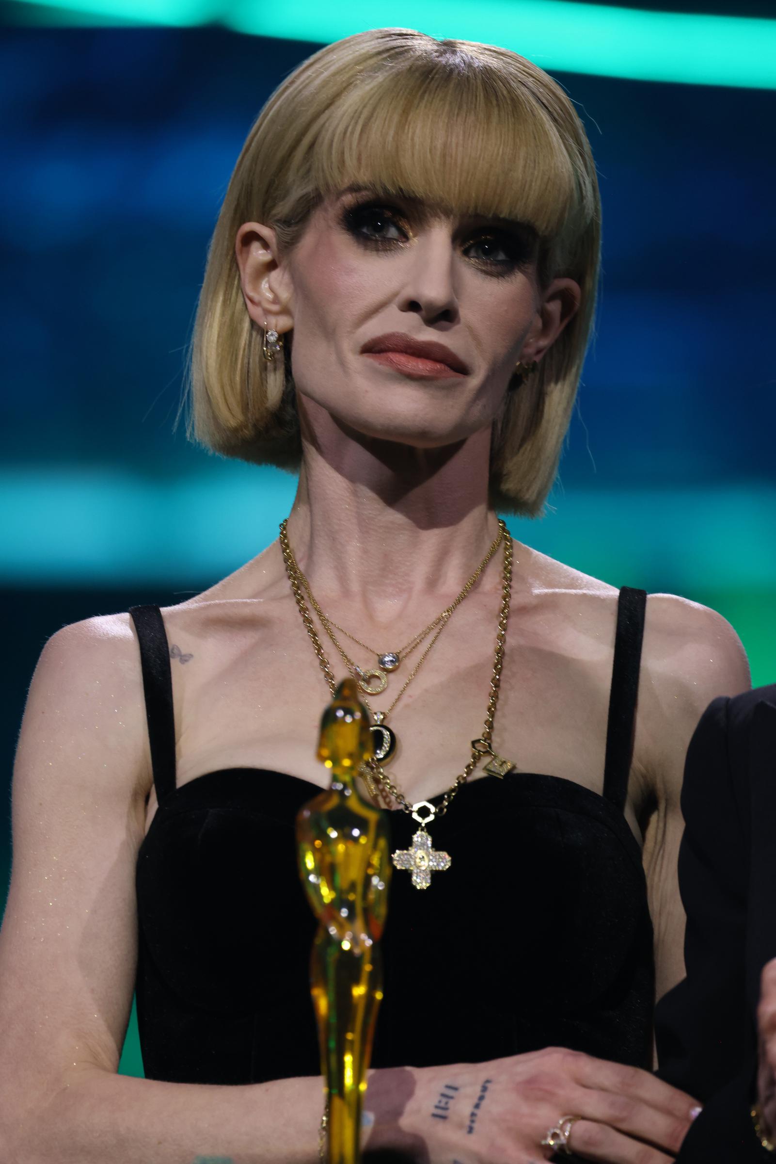 Kelly Osbourne accepts the "Lifetime Achievement" award on behalf of her late father, Ozzy Osbourne, during The BRIT Awards at Co-op Live in England. The television personality wore a black gown with a sleek blonde bob and layered gold jewelry as she took the stage. | Source: Getty Images