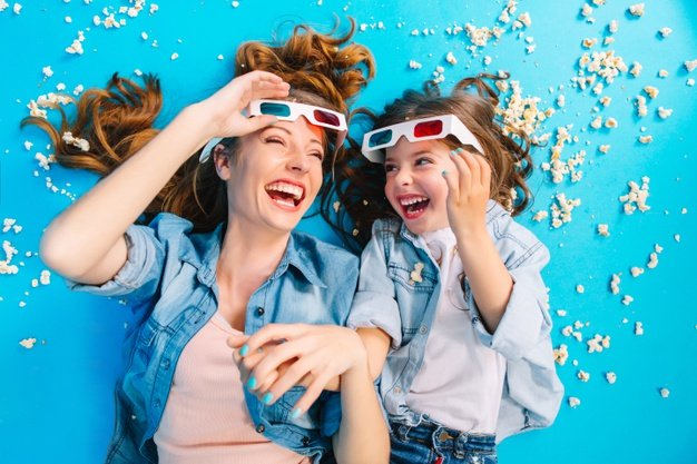 Madre e hija sonriendo rodeadas de popcorn. │Foto: Freepik