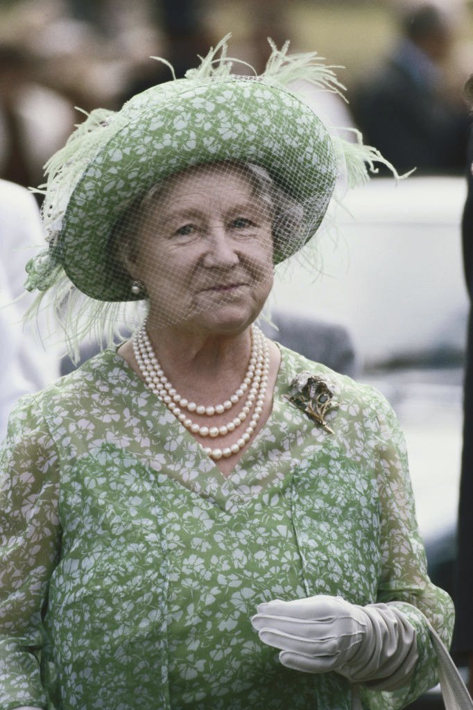 La Reine mère (1900 - 2002), vêtue d'une robe à imprimé floral vert et blanc, d'un chapeau assorti orné de plumes vert pâle et d'un voile en filet, assiste au Sandringham Flower Show sur le domaine de Sandringham à Norfolk, Angleterre, Grande-Bretagne, le 28 juillet 1982. | Photo : Getty Images