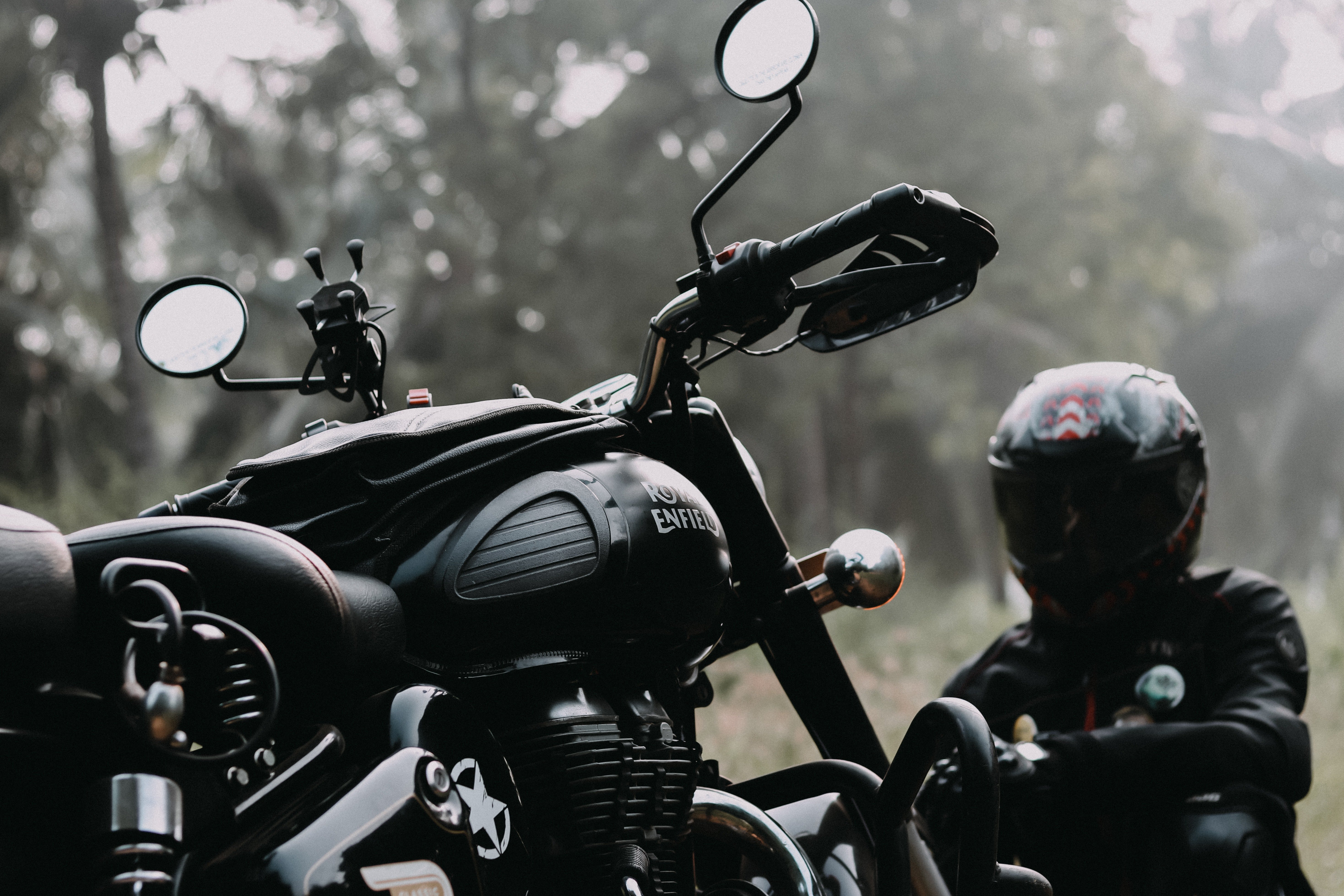 A black motorbike with a rider dressed in black sitting next to it. | Pexels/ Prithivi Rajan
